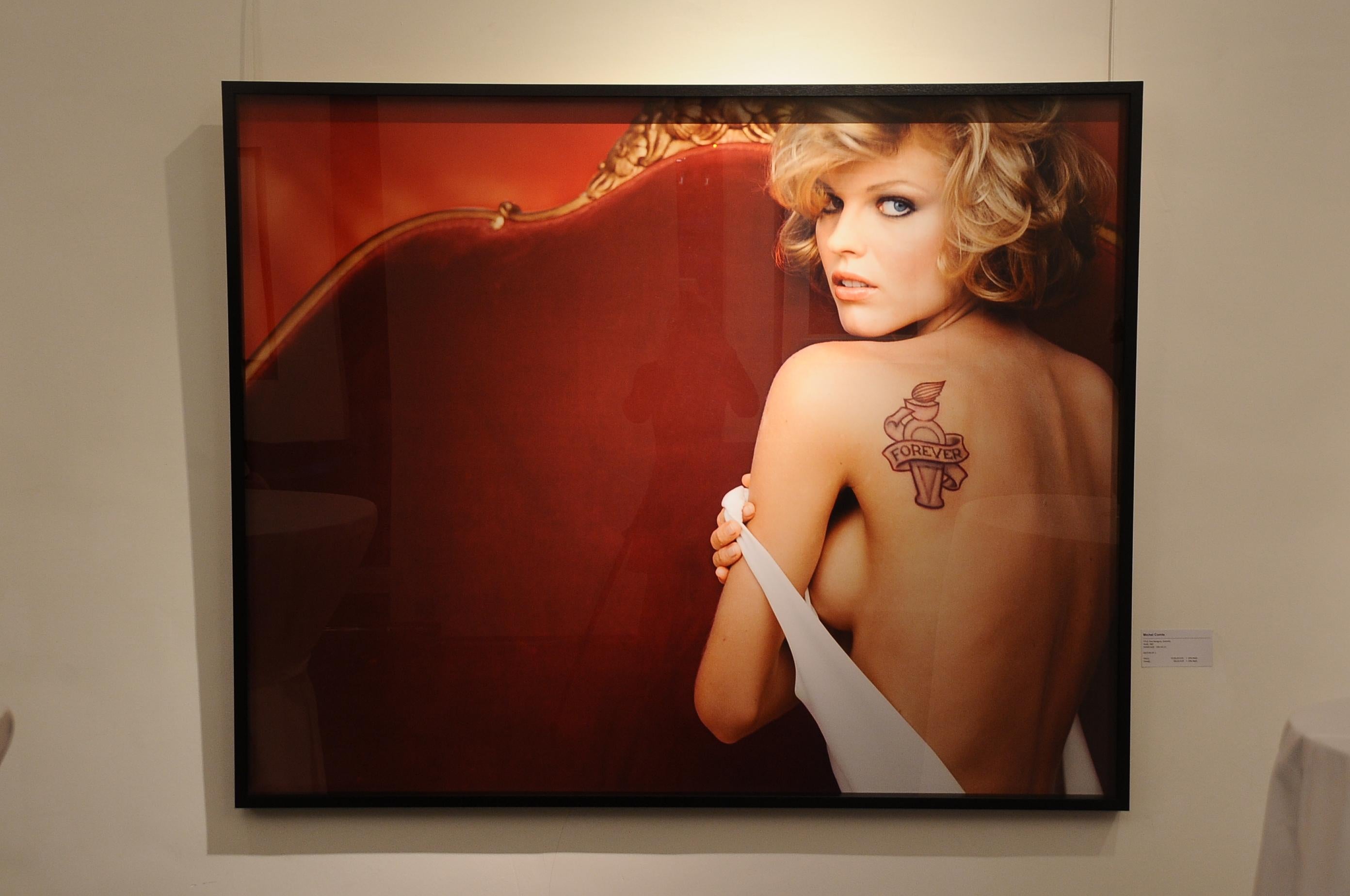 Porträt der Supermodel Eva Herzigova auf dem Sofa, die ihren nackten Rücken mit Tätowieren zeigt – Photograph von Michel Comte