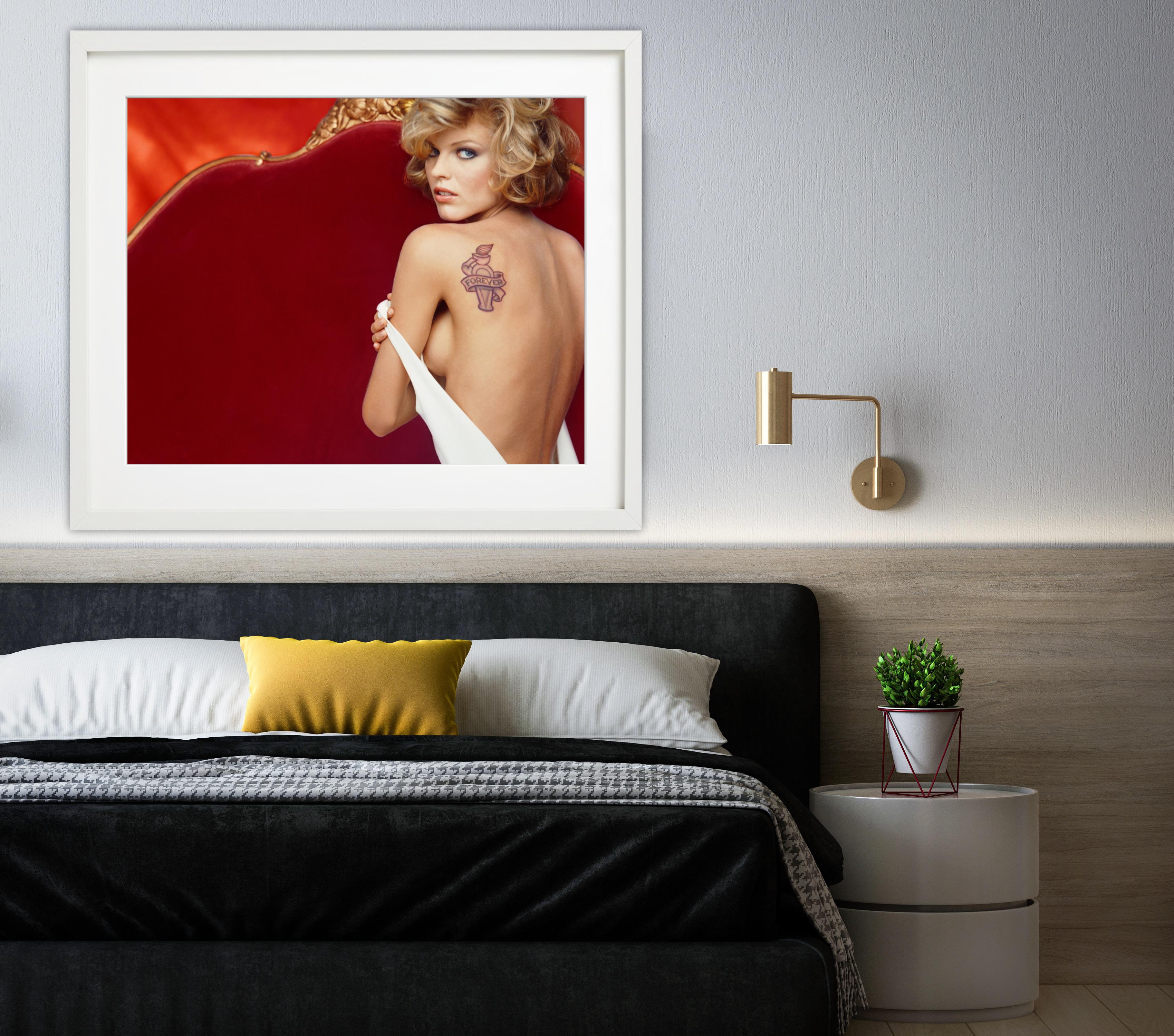 Portrait of supermodel Eva Herzigova on sofa, showing her nude back with tattoo - Red Portrait Photograph by Michel Comte