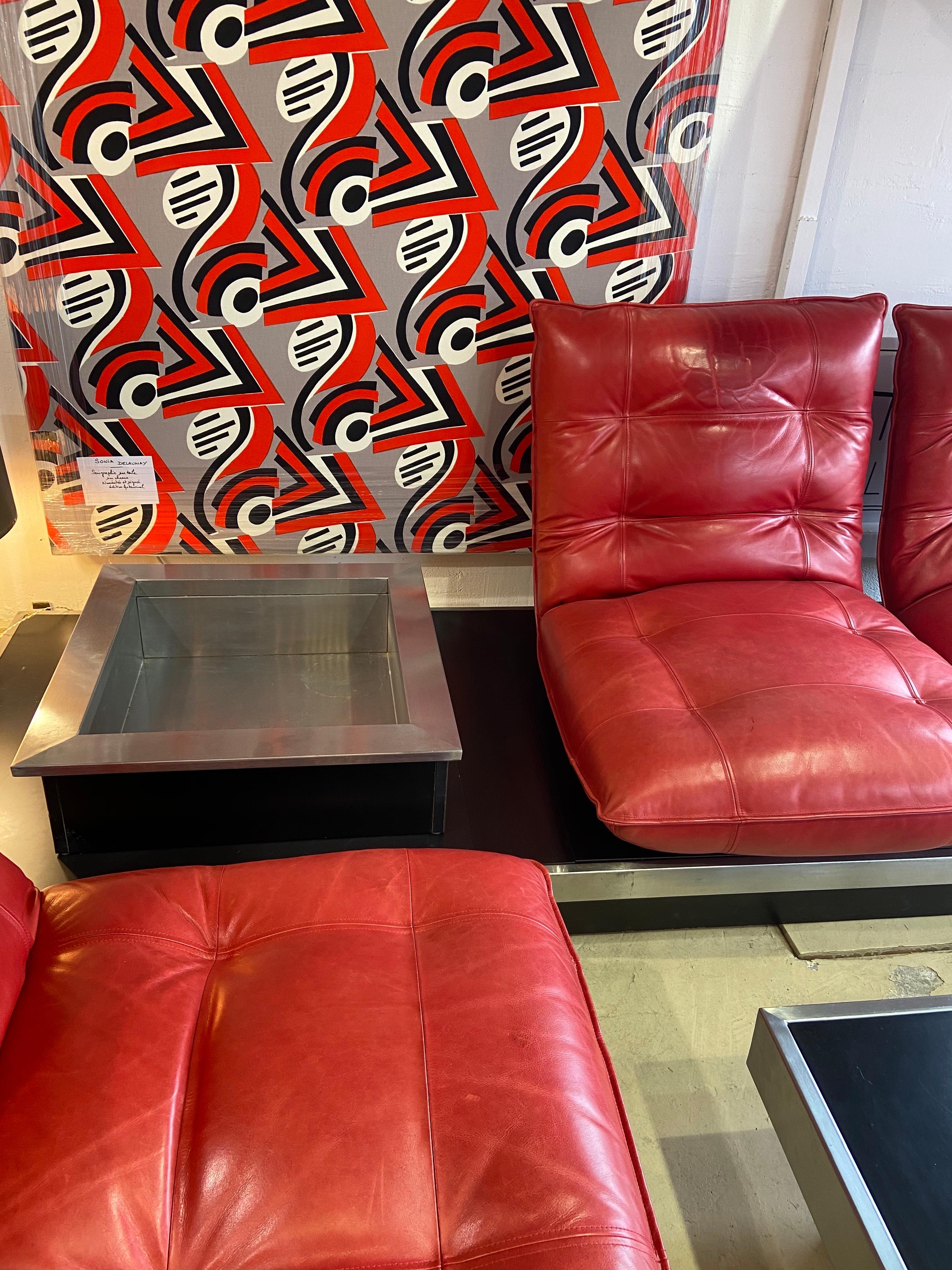 Michel Ducaroy, living room set, 1972
Very rare

Red leather, black melamine and stainless steel

Includes 1 coffee table and 2 benches of 2 armchairs and 1 plant or bottle holder
Bench 1: 270 x 86cm
Bench 2: 194 x 86cm
Table: 111 x