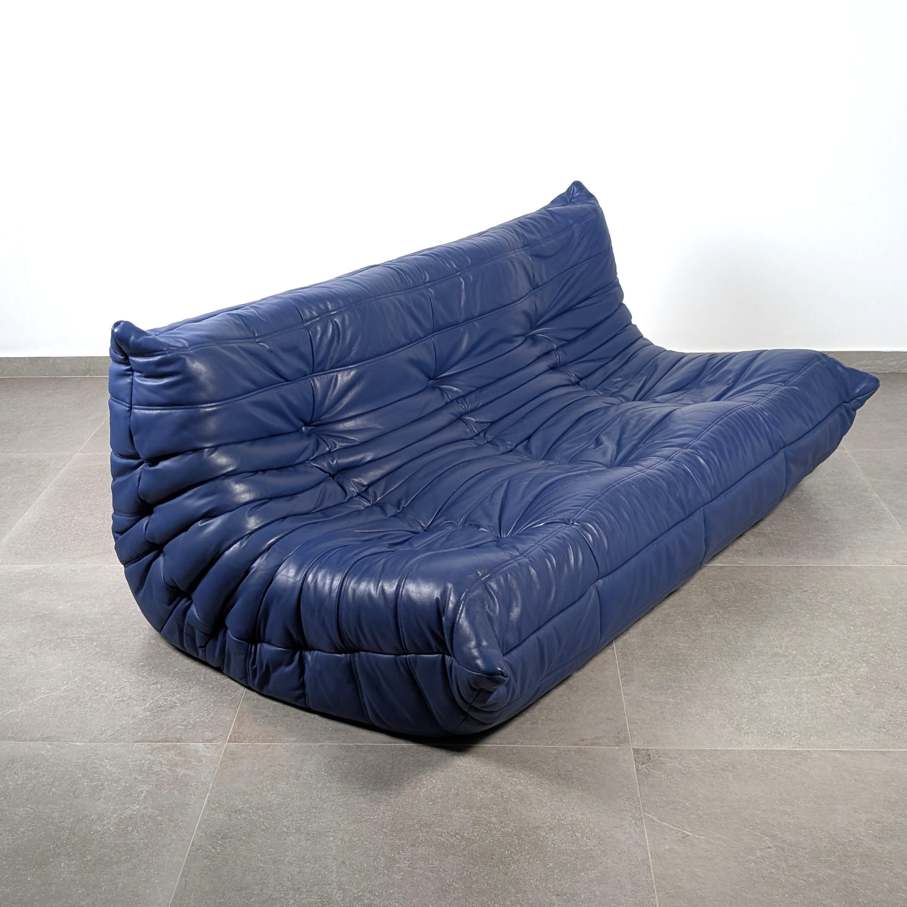 Iconic Togo Sofa designed by Michel Ducaroy for the manufacturer Ligne Roset. Executed in a deep blue leather, this three-seater lounge seat features the pleated craftsmanship and button-tufted detailing essential to the Michel Ducaroy design