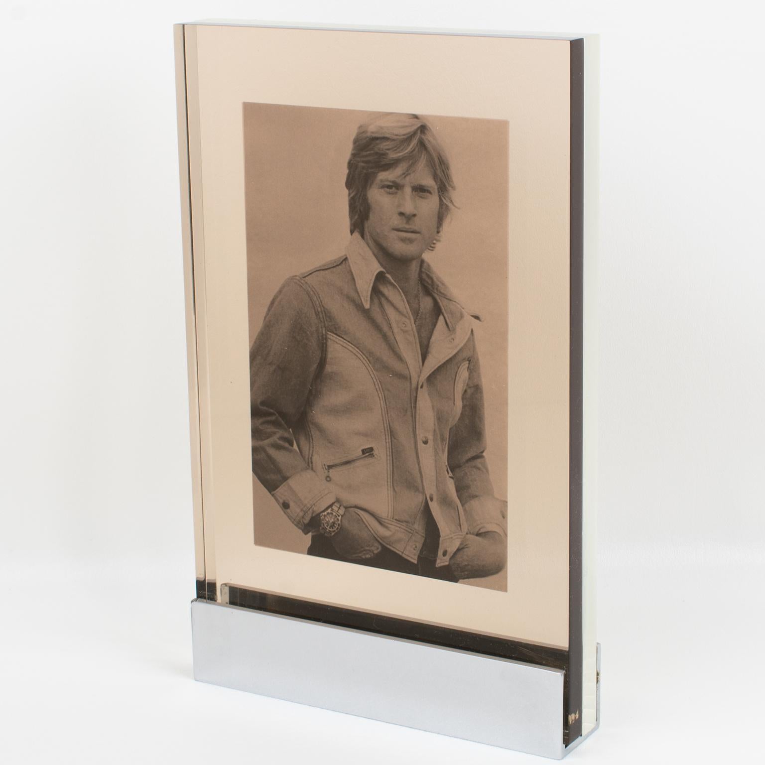 Michel Dumas for Roche Bobois designed this stunning Machine Age metal and Lucite picture frame. The rare photo frame was crafted in France circa 1960. The modernist industrial design boasts a geometric, chromed metal base holder with visible