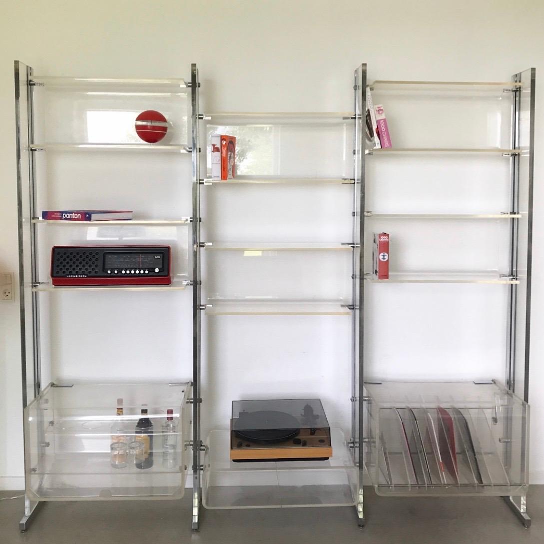 Rare shelf system by Michel Dumas for Roche Bobois, France early 1970s. 

High quality built clear plexi glass and chrome plated details. 

The system consists of a bar, cabinet for vinyl records, 6 U shaped shelves and a large shelf. 4 metal