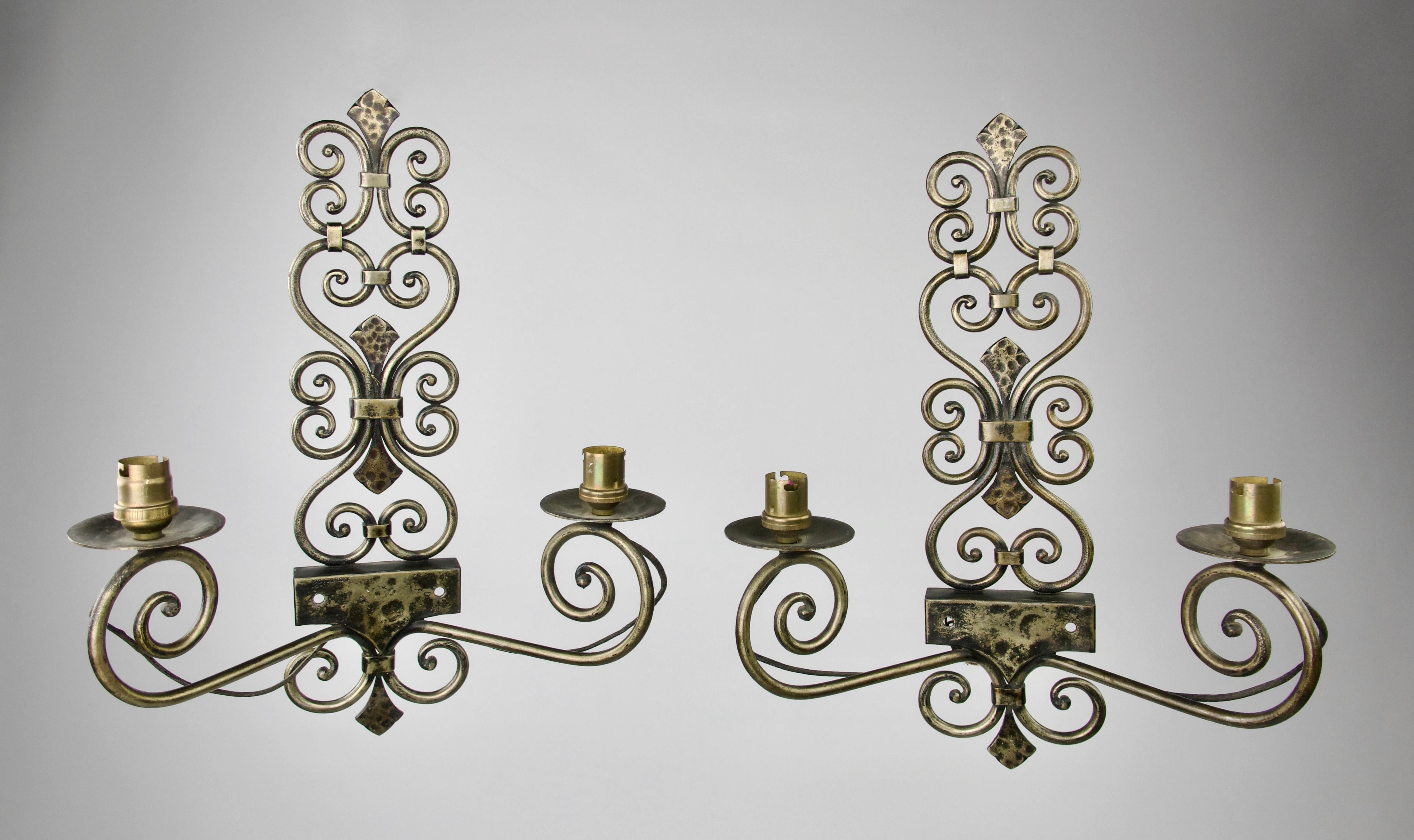 Pair of sconces in hammered wrought iron with two stems by Michel Zadounaisky (1903 - 1983). Body of volutes and interlaces. 
Signed in the front.

Excellent condition. Slight oxydation.

Measures: Height 40 cm - Length 28 cm - Depth 12 cm