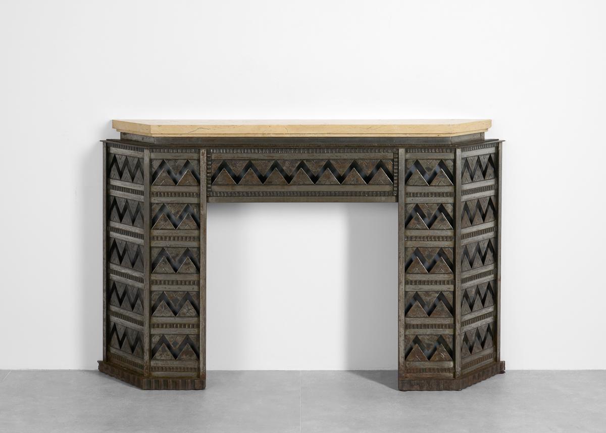 Cette impressionnante cheminée Art déco est réalisée en fer forgé avec des lignes zigzagantes fascinantes et est surmontée d'un luxuriant morceau de marbre de Bourgogne. La partie centrale de la cheminée s'ouvre pour révéler un compartiment