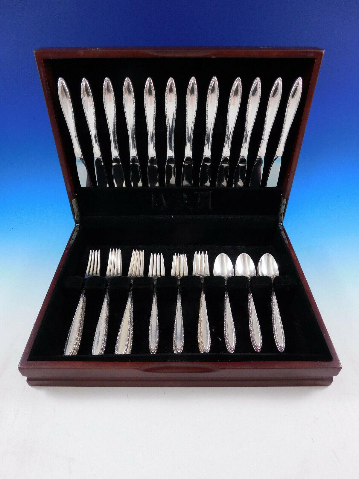 Michele by Wallace, circa 1968, sterling silver flatware set - 48 pieces. This pattern features a modern, slender, pointed handle with a fine lace-like border of design. This set includes:

12 Knives, 9 1/8