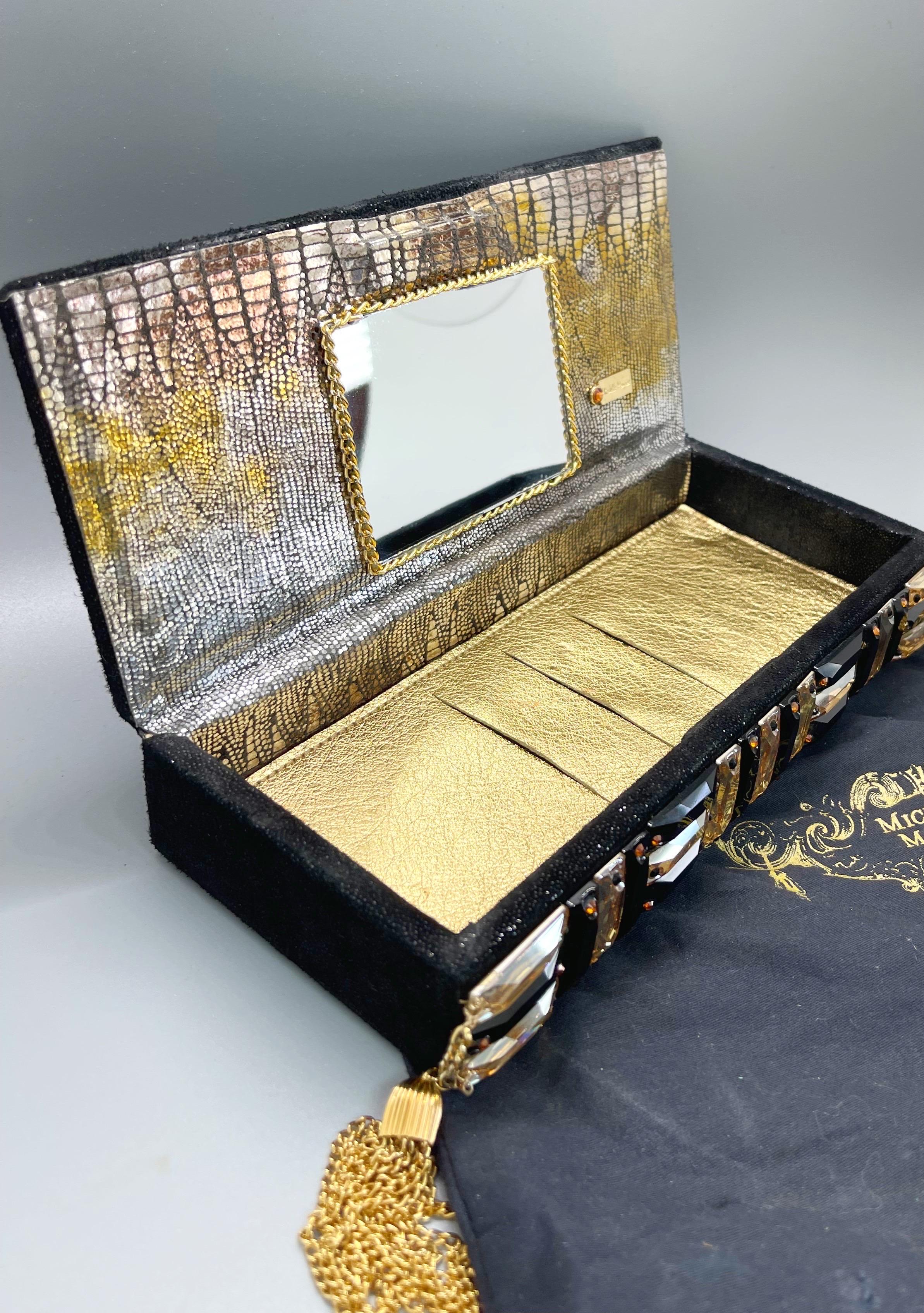 The perfect box clutch to complete any outfit. Magnetic closure. Black stingray embossed, with large rectangle gold and black rhinestones on the top. Gold tassels at each side of the clutch. Built in credit card and ID slots so you don’t need a