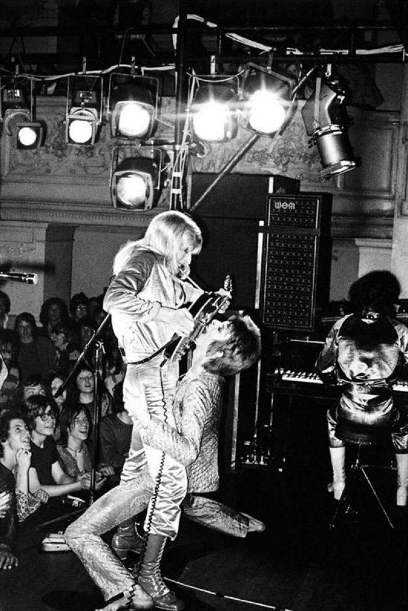 Bowie und Ronson auf der Bühne - limitierte Auflage Mick Rock Estate Print 

David Bowie und Mick Ronson Guitar Fellatio, 1972 (Foto Mick Rock).

Alle Drucke sind vom Nachlass nummeriert.
Die Auflagenhöhe variiert je nach Druckgröße.

Ungerahmter