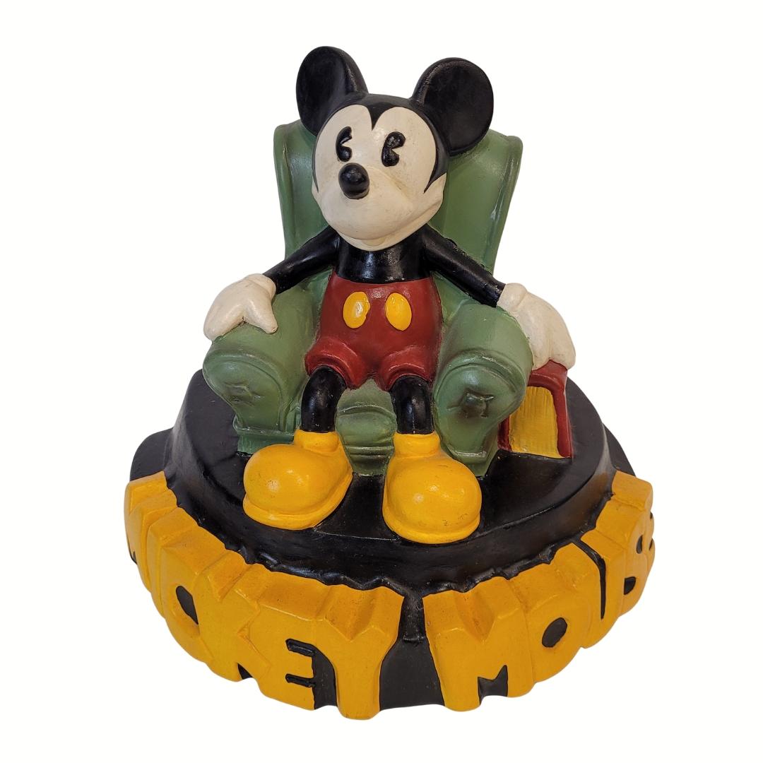Divertente e originale Topolino in ceramica seduto sulla sua sedia da lettura. Questa statuetta da collezione è stata disegnata da Demons & Merveilles, su licenza di Walt Disney, intorno agli anni Novanta. Mostra Topolino sorridente, seduto su una