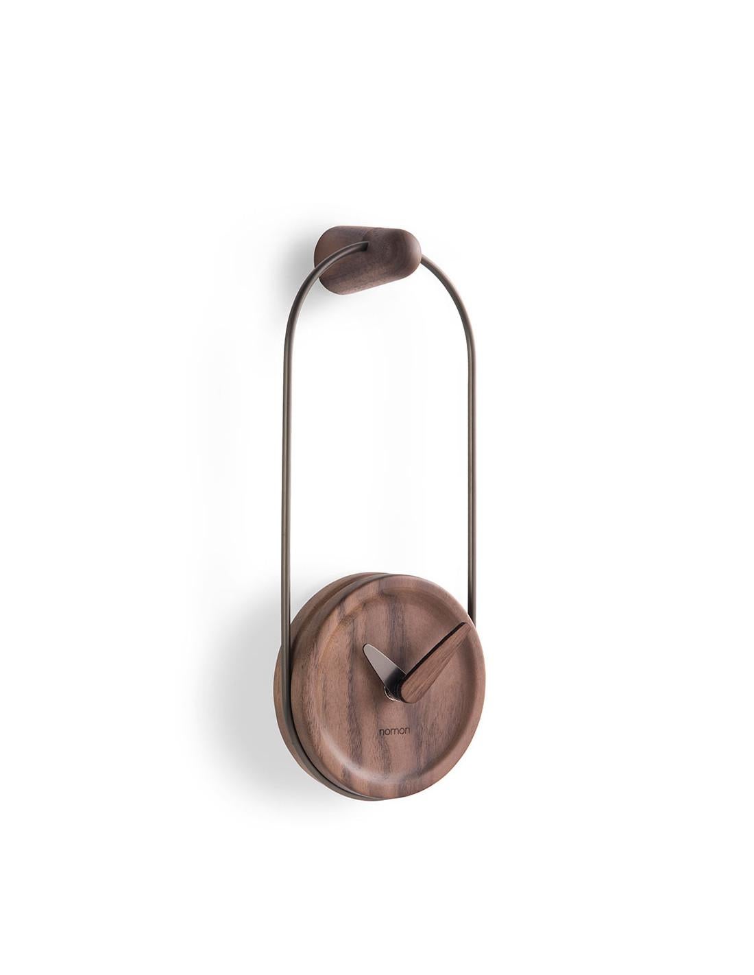 The Micro Eslabón wall clock has been made with a graphite finish brass ring and a walnut or oak case. 
Micro Eslabón wall clock :Ring and hour hand in polished brass or in graphite brass, box and minute hand in walnut or Oak
Each clock is a unique