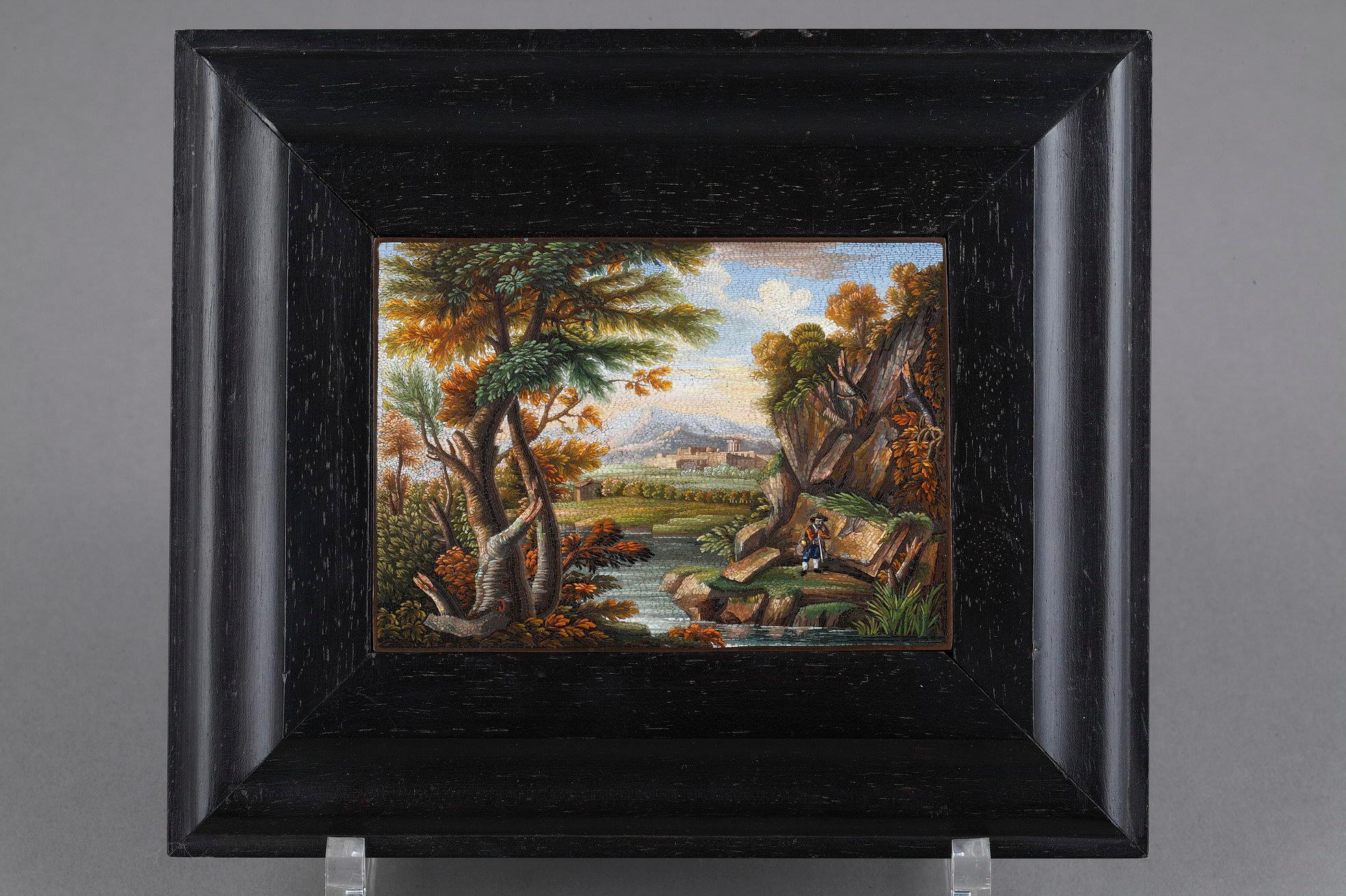 A rectangular micromosaic plate representing a river landscape. This plaque depicting a river on whose left bank is a gnarled tree; on the right bank a peasant stands in front of a rocky ledge with foliage, and in this distance is a town or ruin and