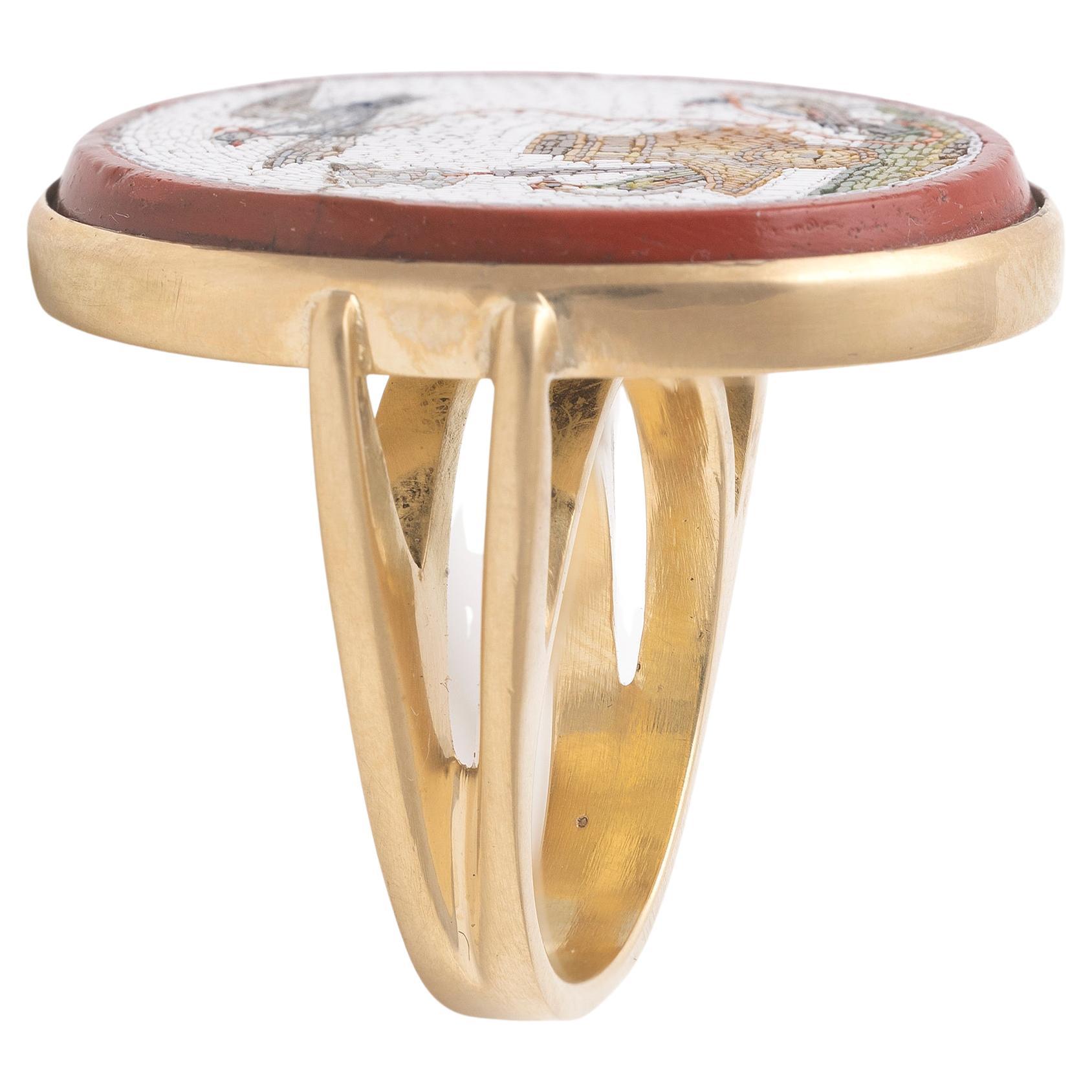An oval micromosaic representing Allegory of Love, cream color background and red border, mounted in yellow gold as a ring. 
Dimensions cm 2,8 x 2,3cm ca - Size: USA 7
Weight: 16,34