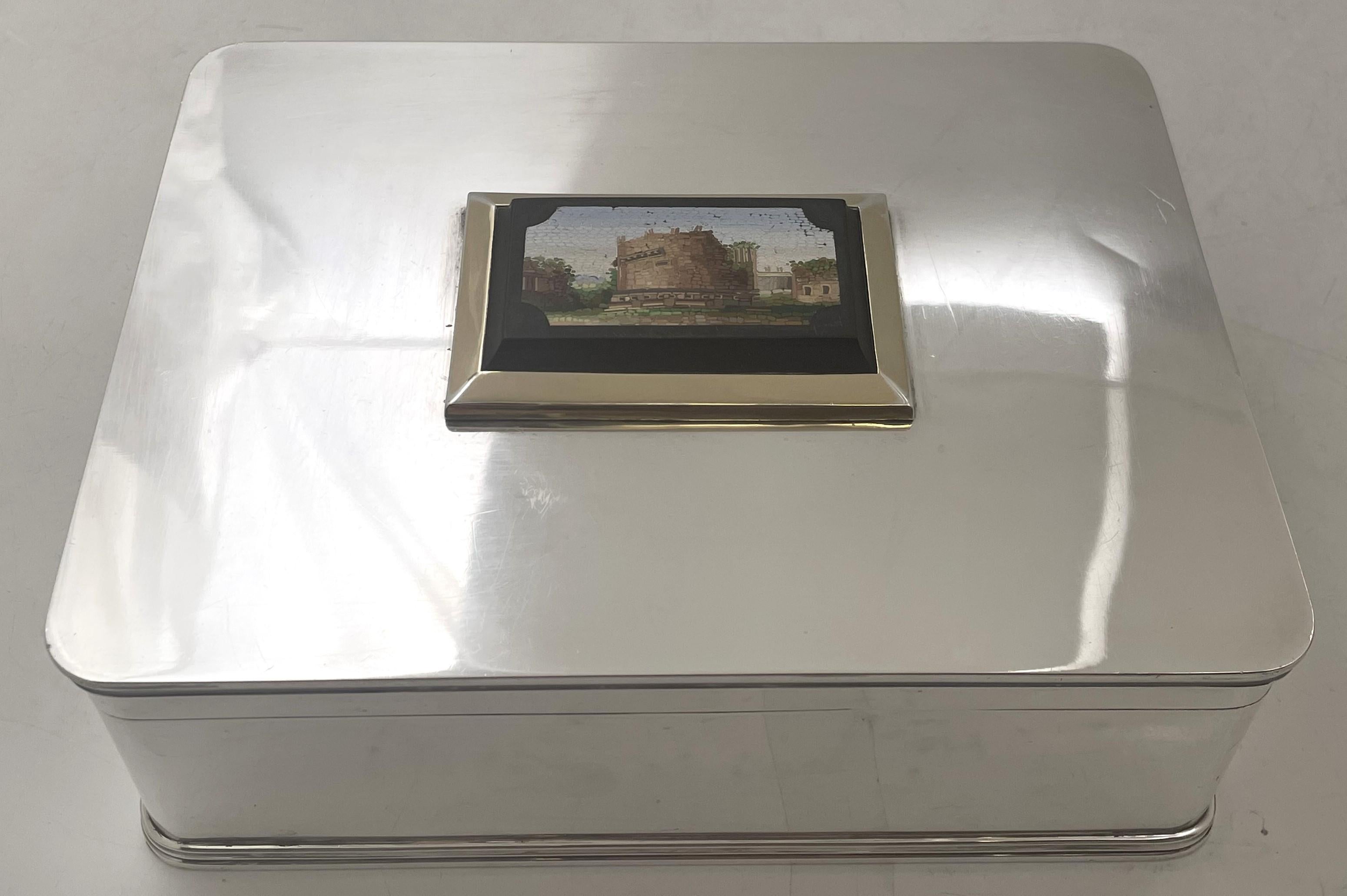 Humidor o portasigari in argento sterling italiano, ornato da un micromosaico sulla parte superiore raffigurante il Colosseo e il Foro Romano, parzialmente dorato intorno al bordo del micromosaico, in un elegante disegno geometrico. Misura 8'' per 6