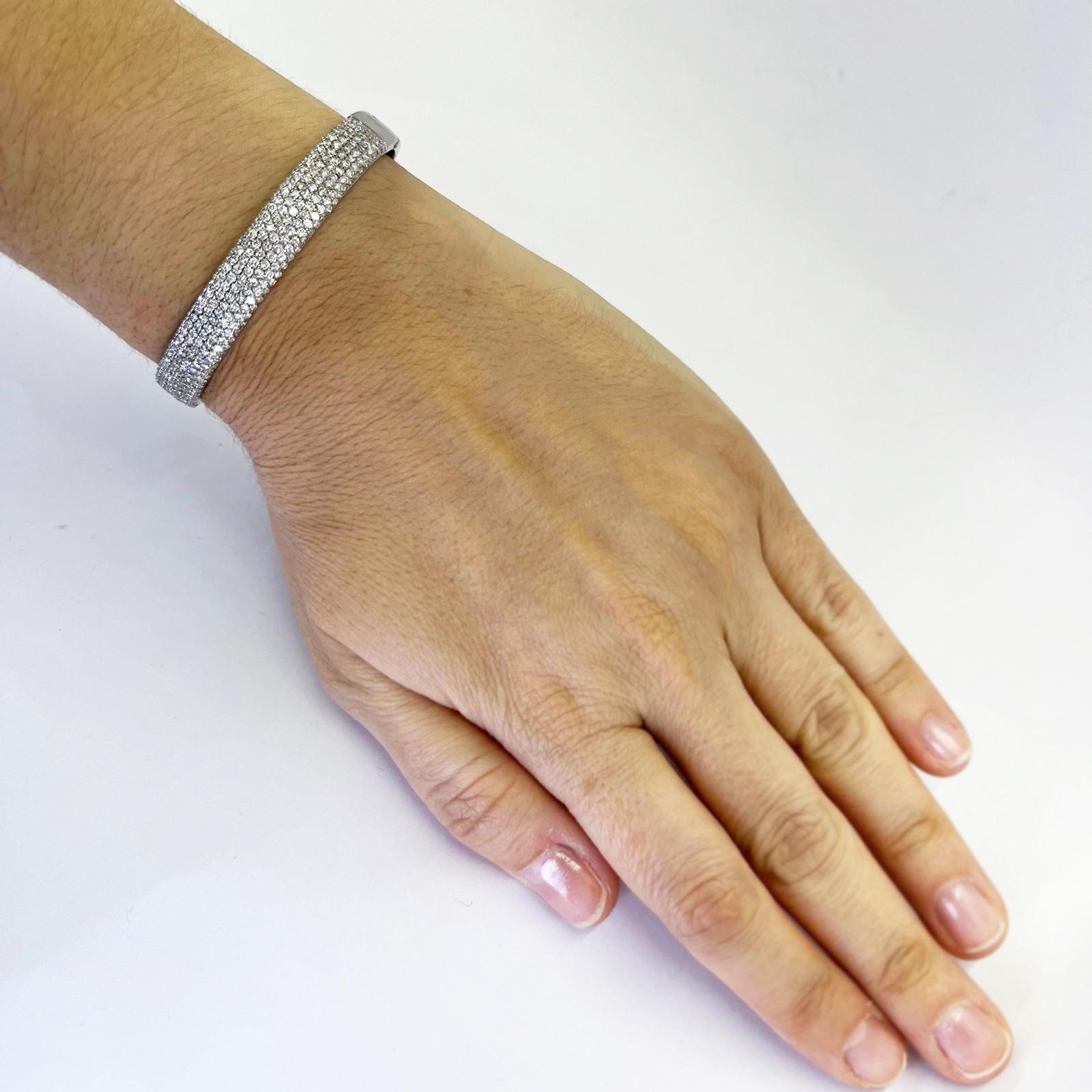 18 karat white gold 8.5mm wide micropave bangle featuring 312 round brilliant cut diamonds of VS clarity and G color totaling 2.67 carats. Hinged design with hidden side clasp and safety bar. High polish bottom with easy to clean open back setting.