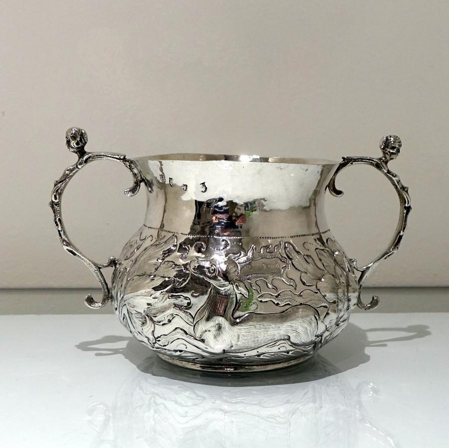 A very beautiful Charles II porringer decorated with delightful hand chased scenes of a dog chasing a “fleeing” deer through foliate surrounds. The upper section of the body is plain in design for decorative contrast and there are two stylish