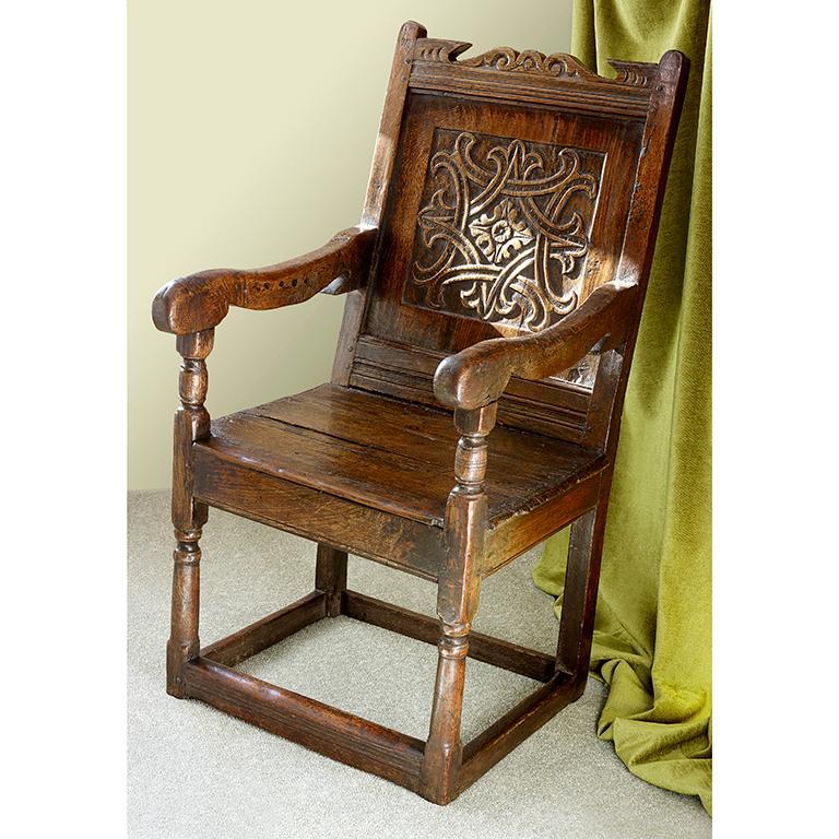 A mid-17th century carved oak wainscot chair with carved back panel.