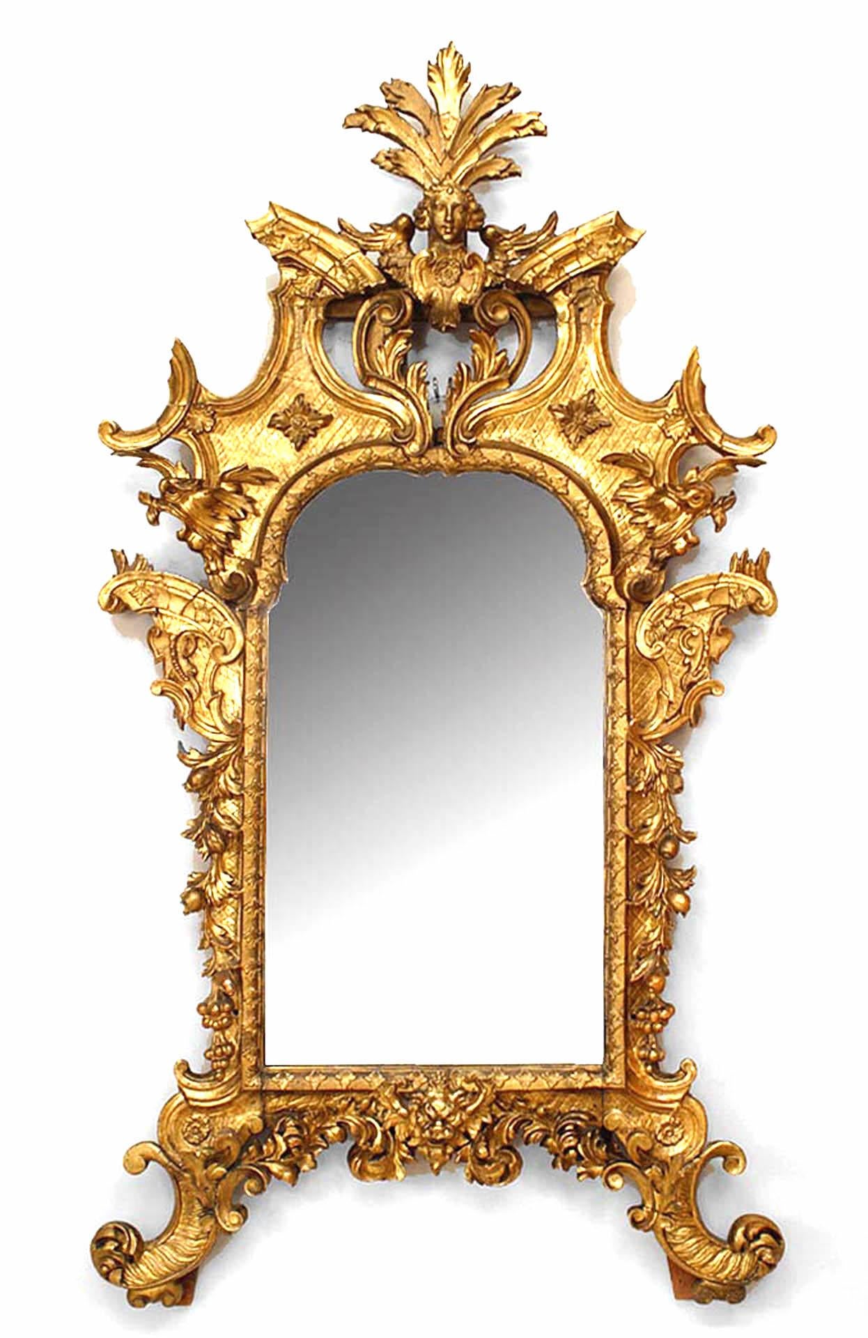 Italian Rococo (Florence, mid-18th Century) giltwood wall mirror with a carved scroll and floral motif and an Apollo mask crest pediment.
