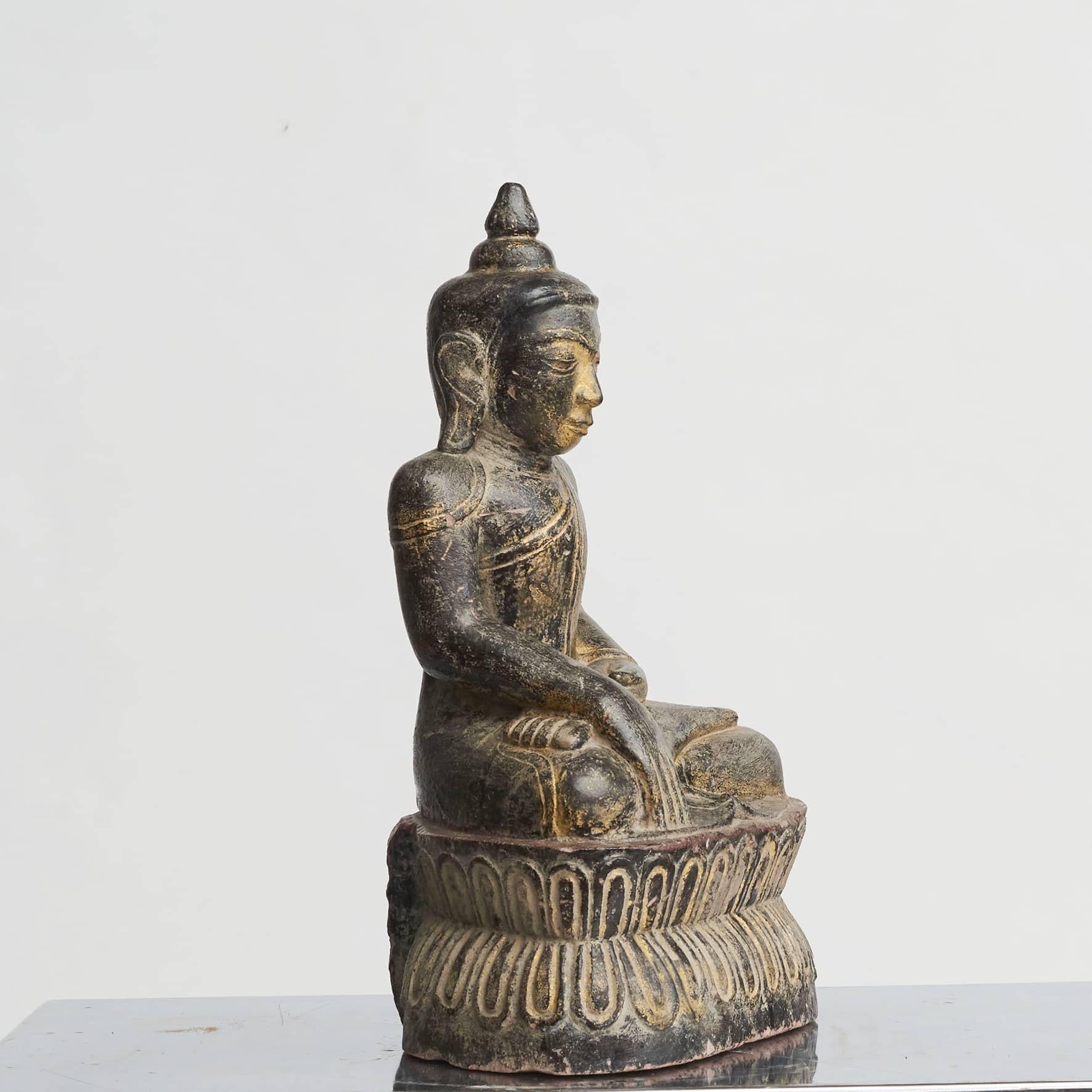 A mid 18th century Burmese stone Buddha seated in Bhumisparsha mudra position* (“calling the earth to witness”).
Black-red lacquer with remnants of gilding.
Many fine details.
A very fine piece in good condition.

*A mudra in Buddha statues is