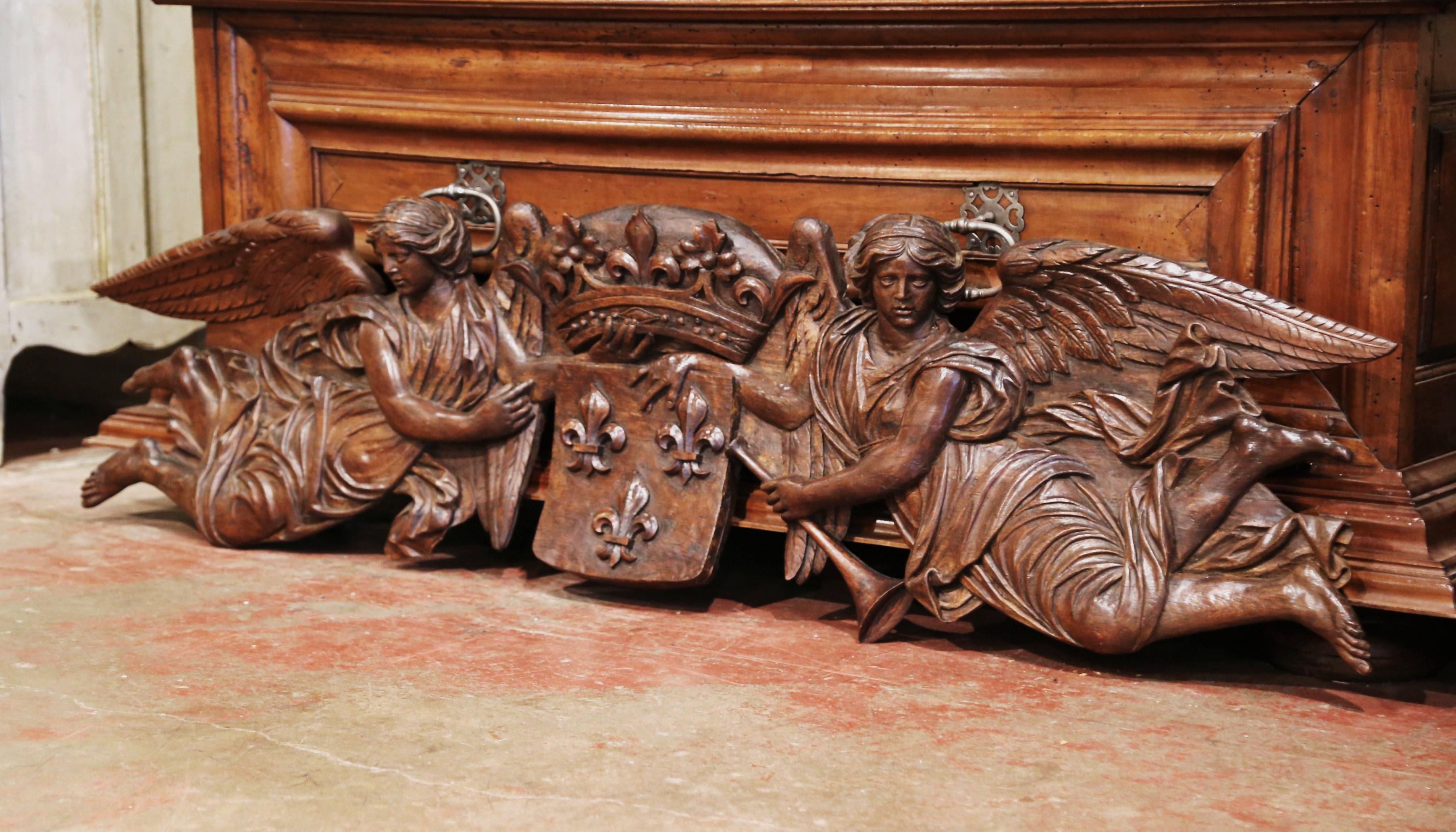 Decorate a man's study or an over door with this important antique carving. Crafted in France circa 1650 and made of oakwood, the six foot carved piece features two winged angels with trumpet holding a crest representing Louis XIV coat of arms