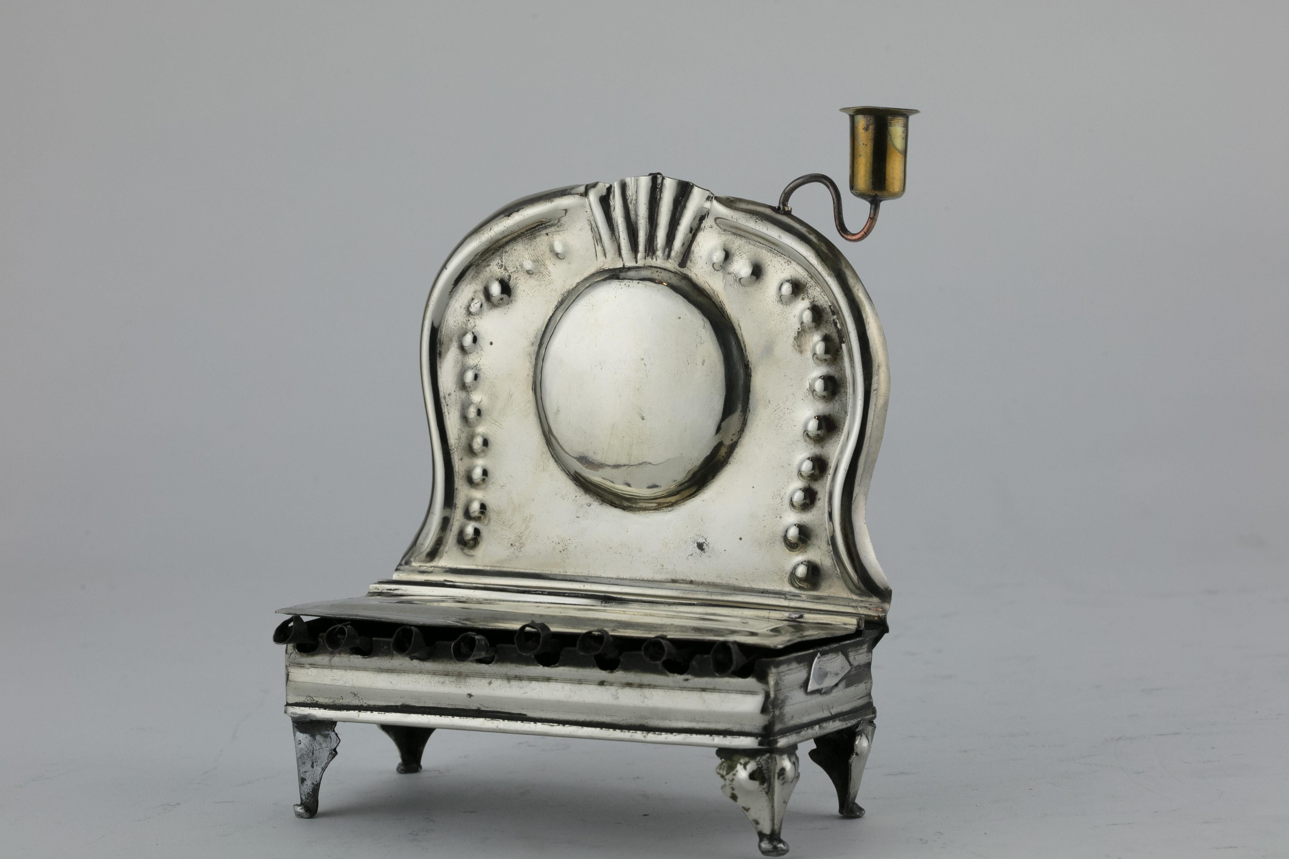 Handmade silver plated brass Hanukkah Lamp, the Netherlands, circa 1750.
On four legs in bench form. Fronted with covered oil container, each oil section with hand wrought wick holder. Backplate hammered with reflective panel.

Every item in Menorah