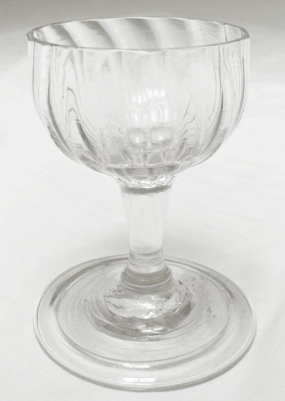 Un elegante bicchierino da dessert/gelatina, Eleg. A metà del XVIII secolo, a forma di coppa aperta su gambo semplice con piede ripiegato. Le nervature modellate e leggermente a spirale sono superbe.
Altezza 3 1/16, diametro base 2 3/8