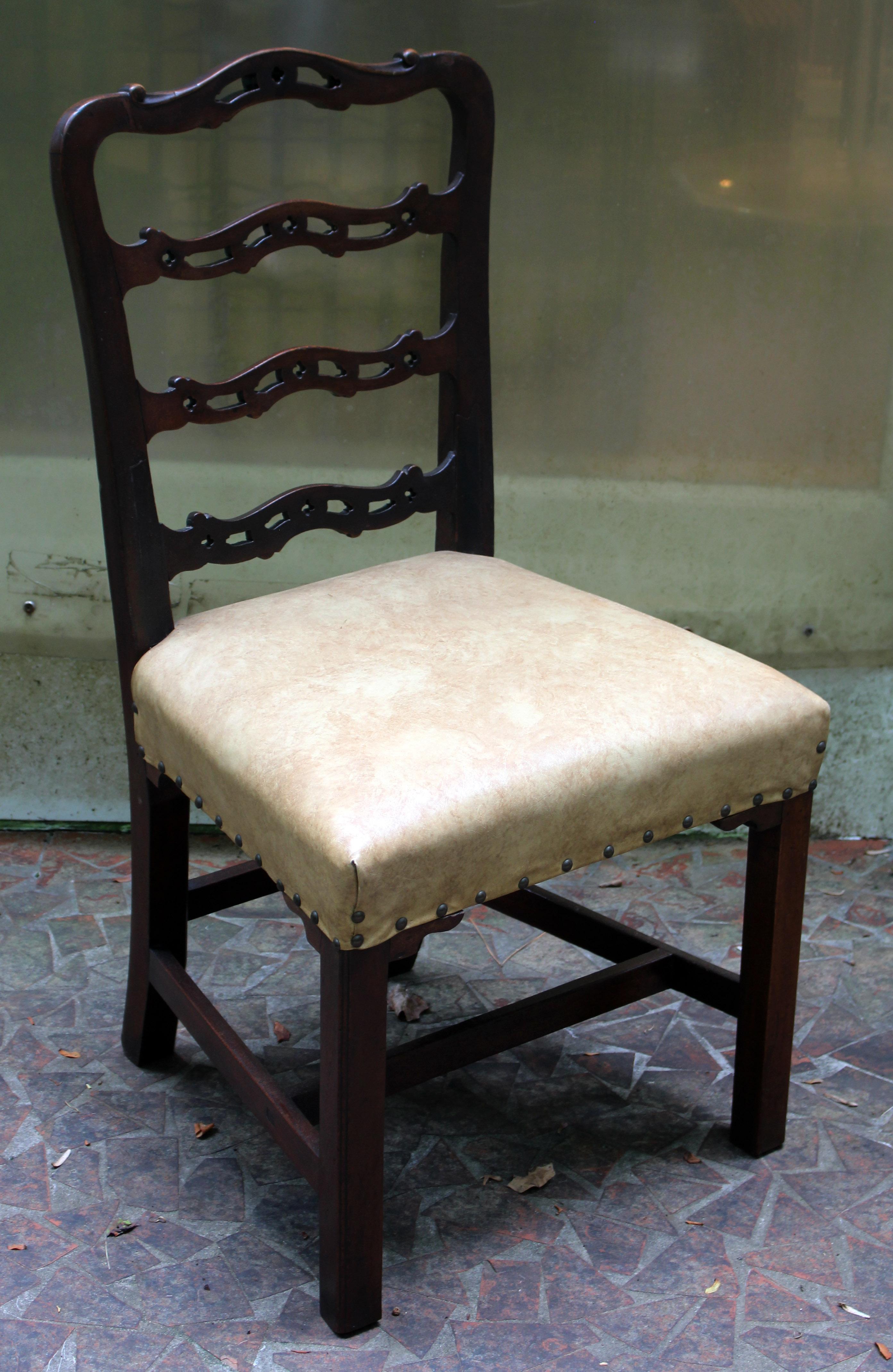 A George III side chair of good, sturdy size. English, c.1760, mahogany. The wavy ladder back with Gothick open cut-work typical of Chippendale design. Stretchered, square molded legs with shaped decorative seat returns. Faux leather upholstery with