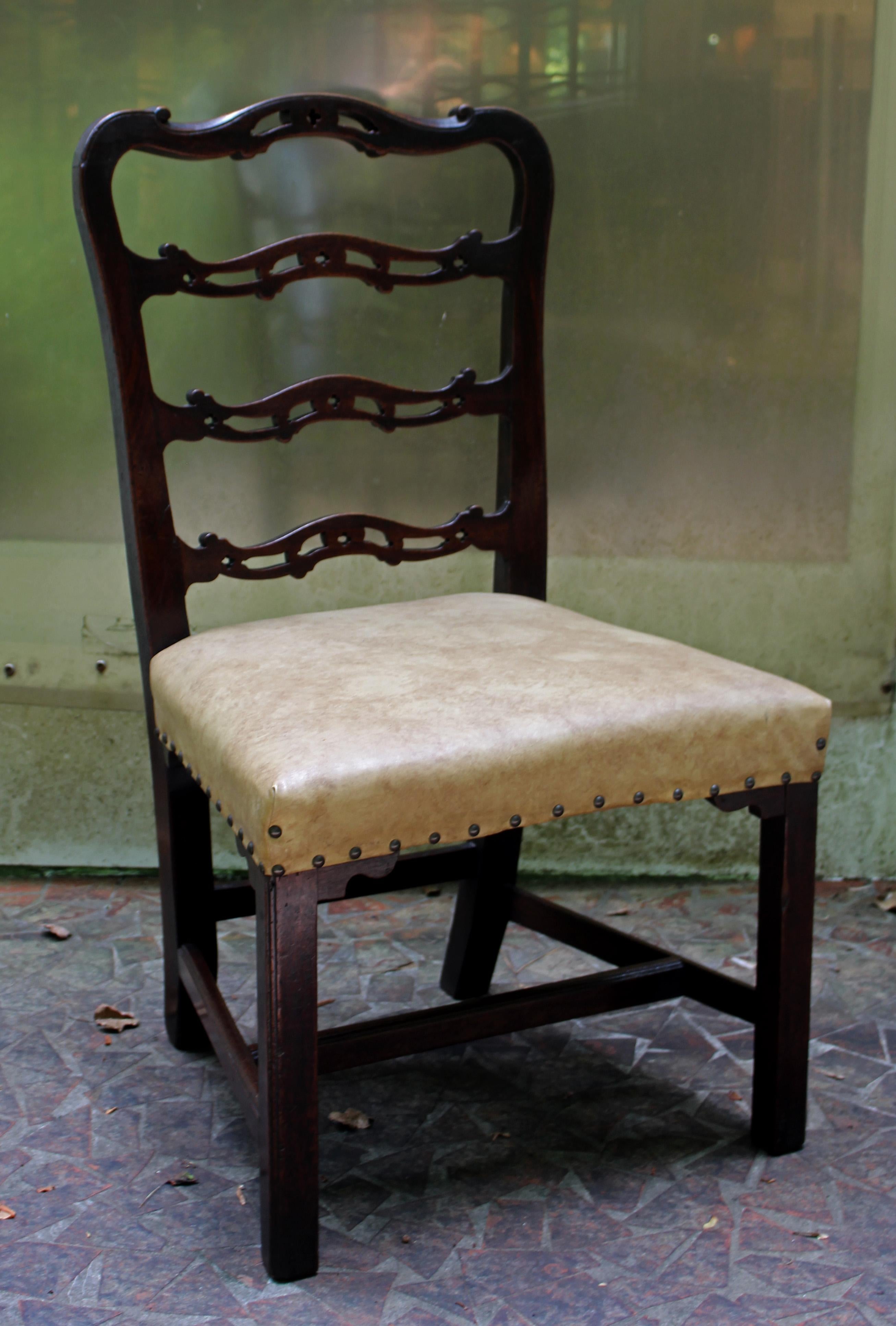 A George III side chair of good, sturdy size. English, c.1760, mahogany. The wavy ladder back with Gothic open cut-work typical of Chippendale design. Stretchered, square molded legs with shaped decorative seat returns. Faux leather upholstery with