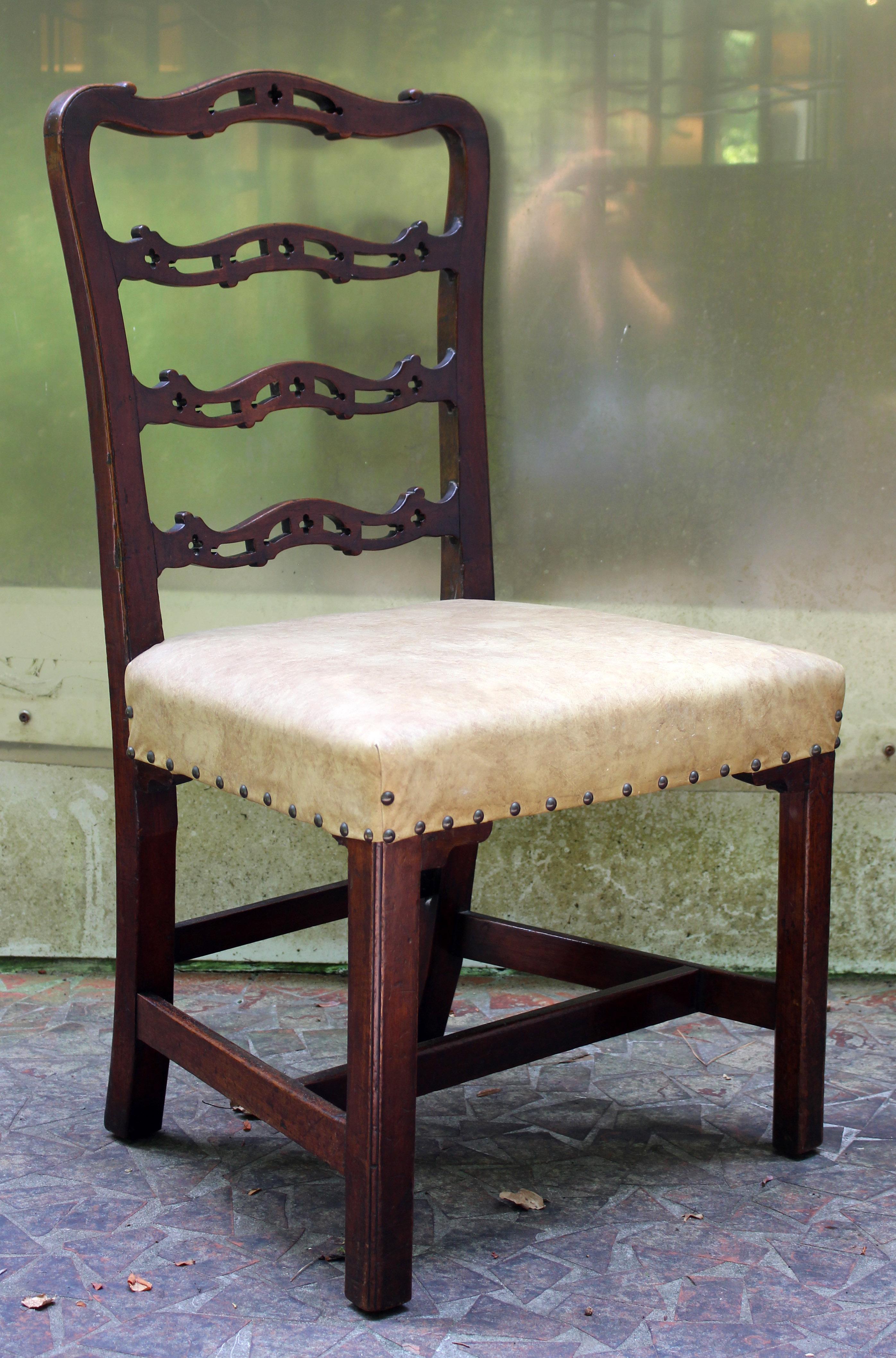 A George III side chair of good, sturdy size. English, c.1760, mahogany. The wavy ladder back with Gothic open cut-work typical of Chippendale design. Stretchered, square molded legs with shaped decorative seat returns. Faux leather upholstery with