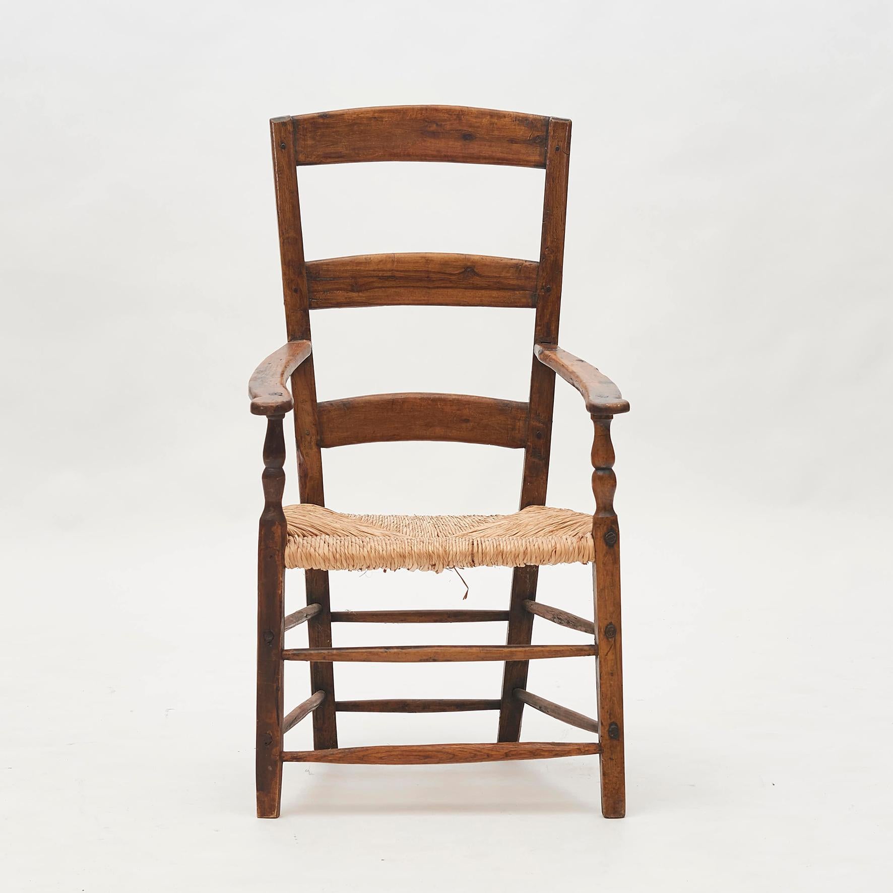 Fine example of English ladder back armchair in Yew wood. England, early 18th century. Appears untouched with beautiful original patina. The seat is a hand woven rush seat and very sturdy. The seat is of later date than the rest of the chair. The