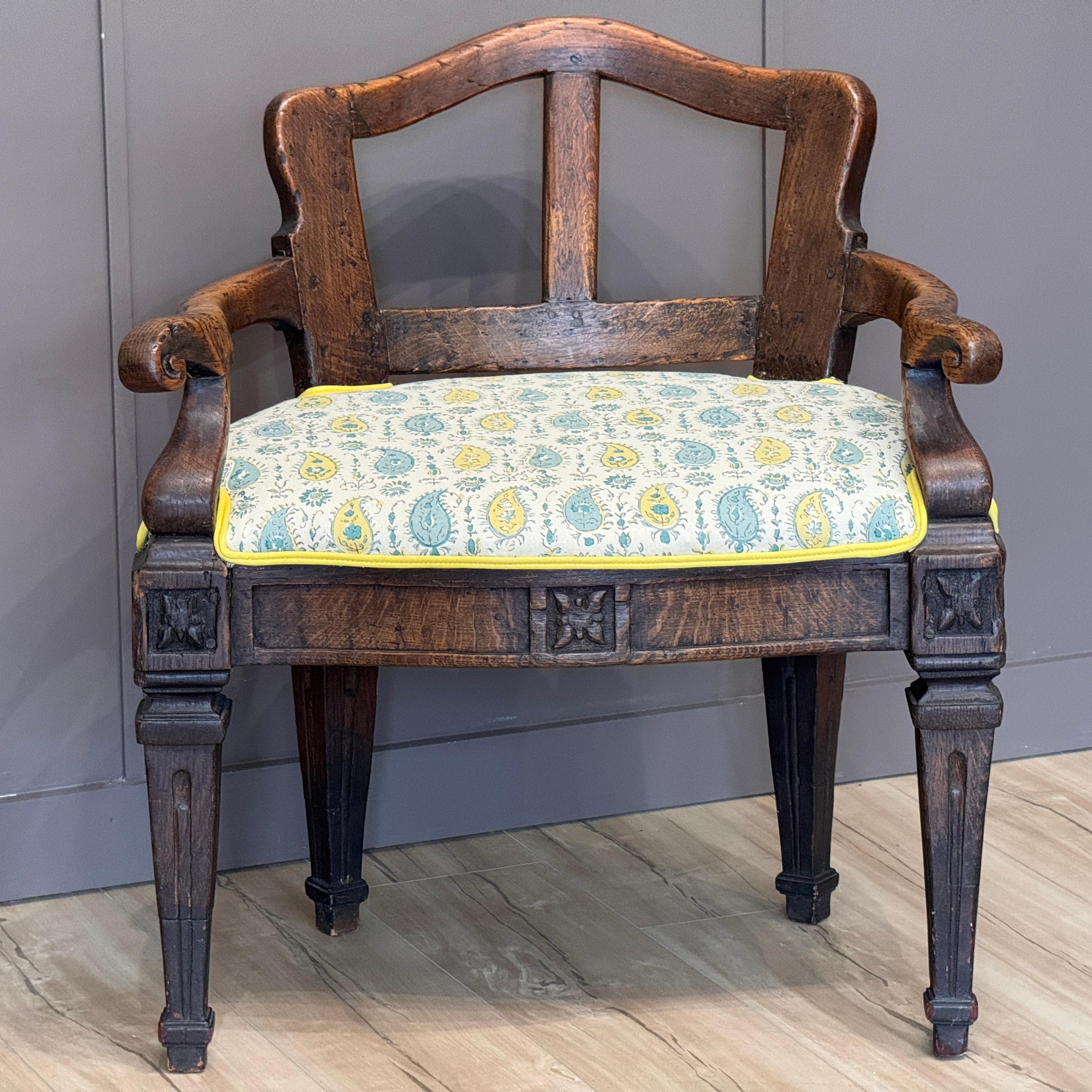 Poltrona francese della metà del XVIII secolo, realizzata in olmo con braccioli sagomati e gambe affusolate con rosette intagliate agli angoli. Il rivestimento aggiornato in un vivace tessuto paisley con profili a contrasto è un complemento fresco