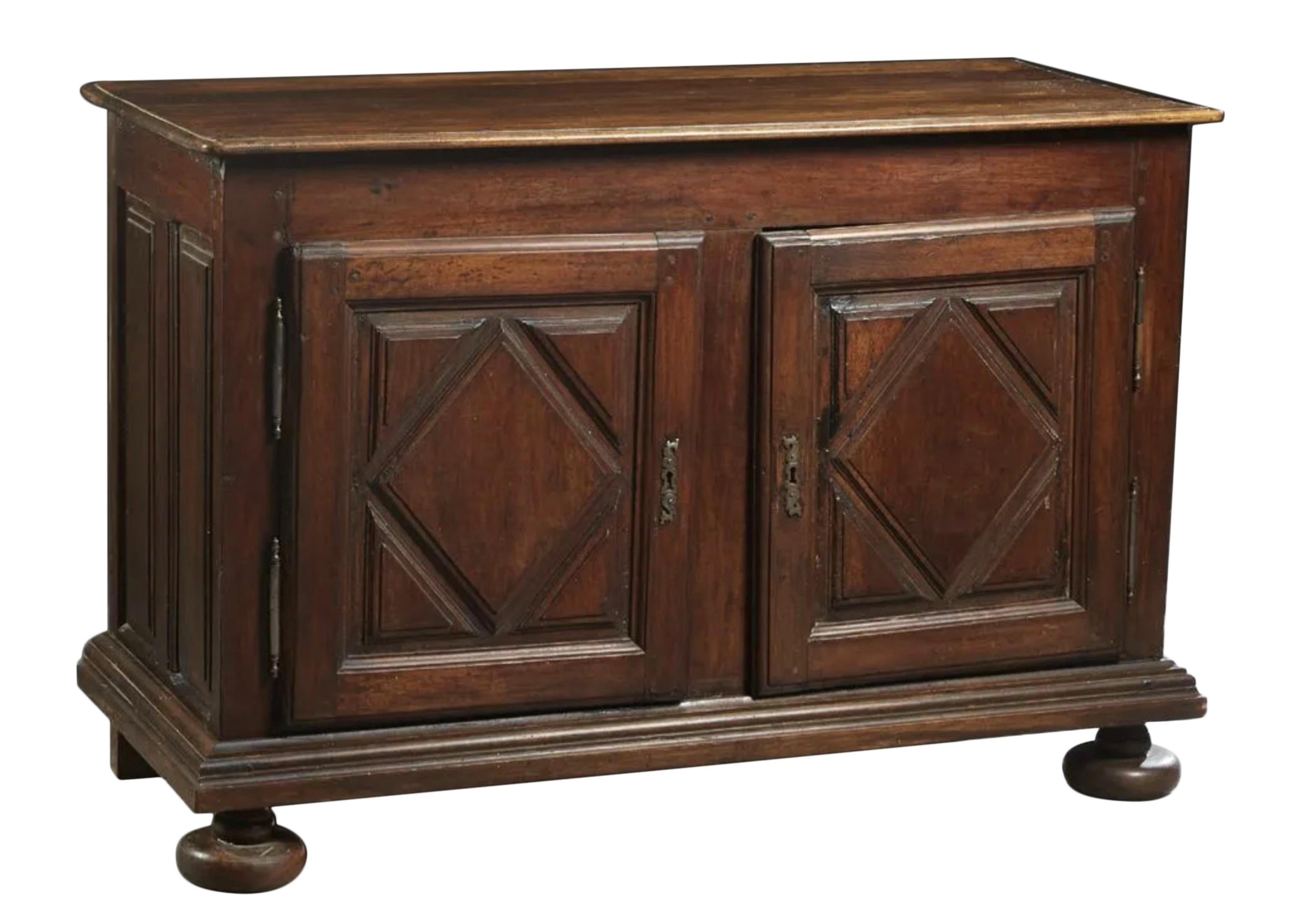 French Louis XIII Style Carved Walnut Sideboard, 19th c., the stepped rounded edge and corner top over double cupboard doors with applied geometric decoration and iron fiche hinges and escutcheons, on a stepped plinth base, on large turned bun feet,