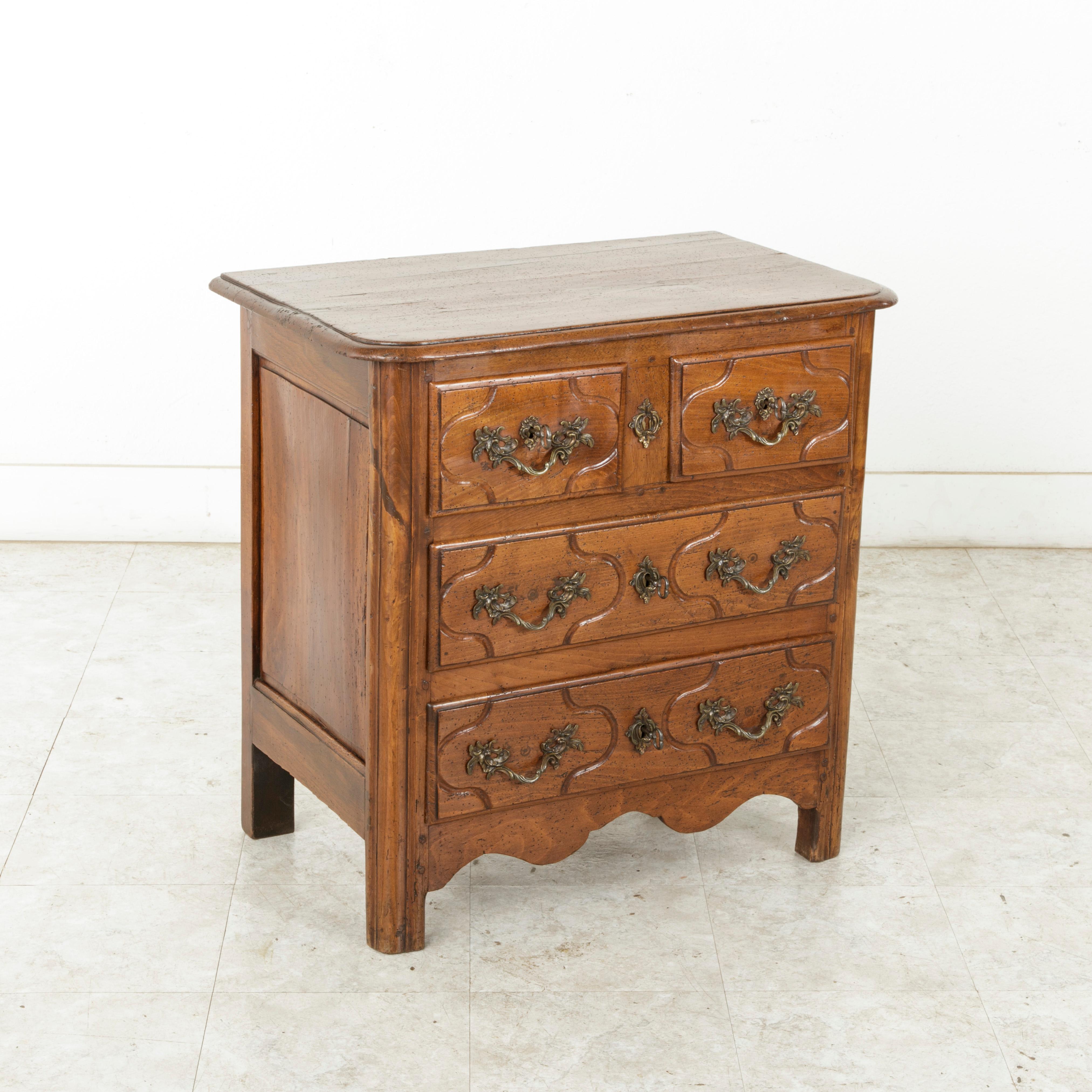 This mid-18th century French Louis XIV period hand carved chestnut commode or chest is from the Ile de France region surrounding Paris. Of an unusual small scale originally meant for a Paris apartment, this piece features four drawers of dovetail