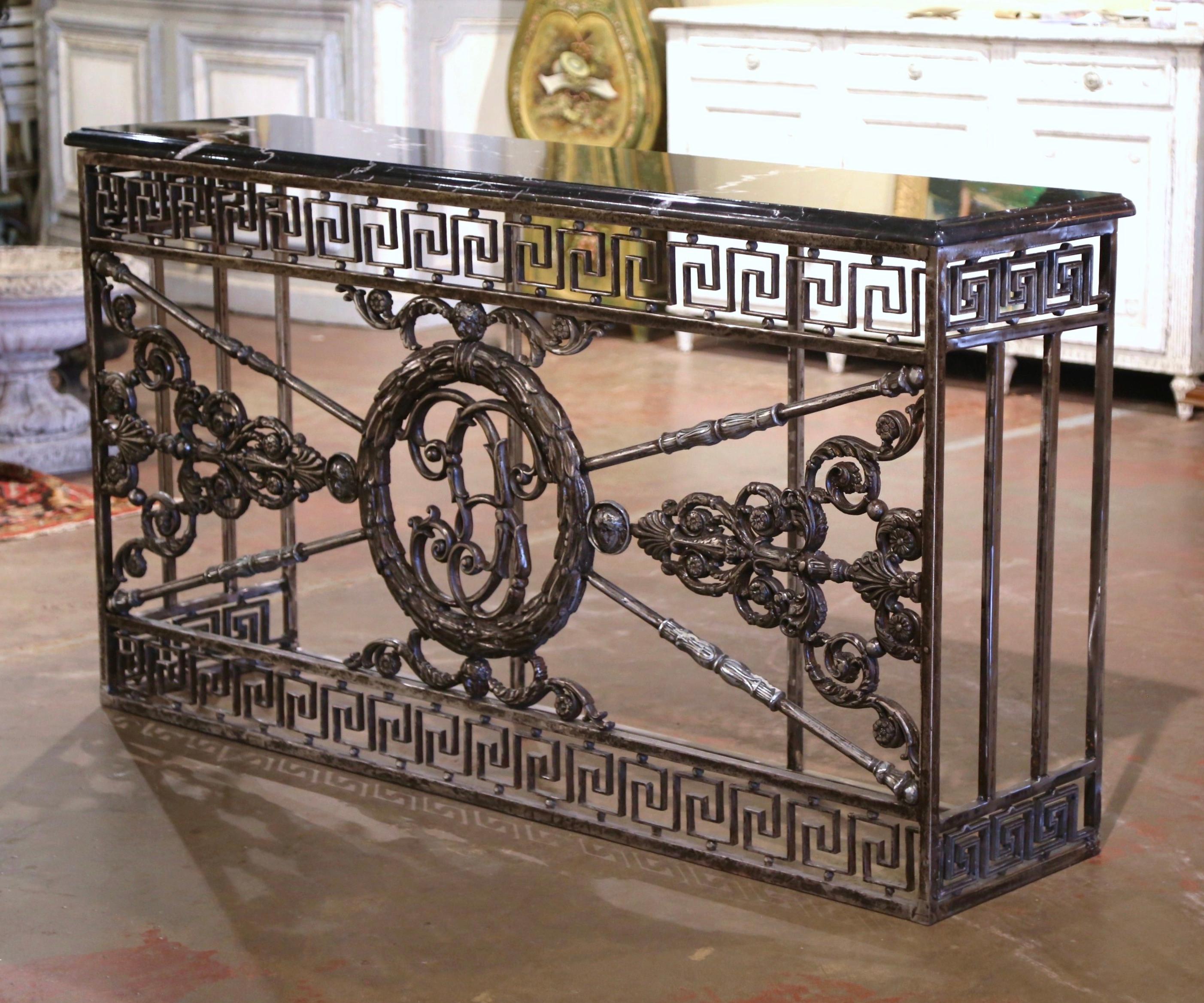 Forged in France circa 1750, the antique console table base stands on straight feet connected with a bottom stretcher. Long and narrow, the Louis XIV style table with Greek motifs at the top, features intricate scrolled decor, leaf motif, and