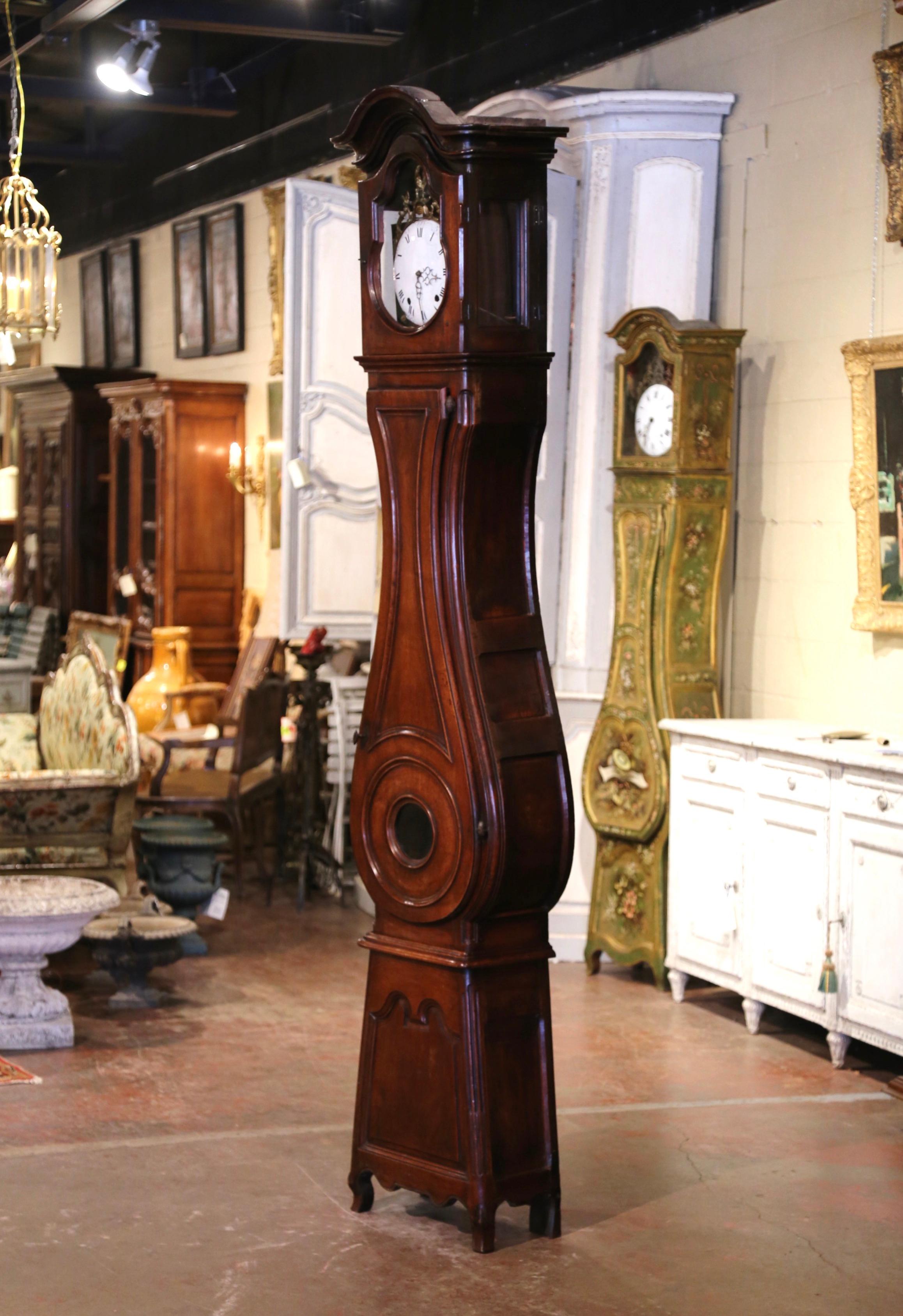 Crafted in Lyon, France, circa 1760 and built in two sections, the antique fruitwood tall case clock stands on curved feet over a scalloped apron, and features beautiful lines including a bonnet top over a violin shape body. The case with carved