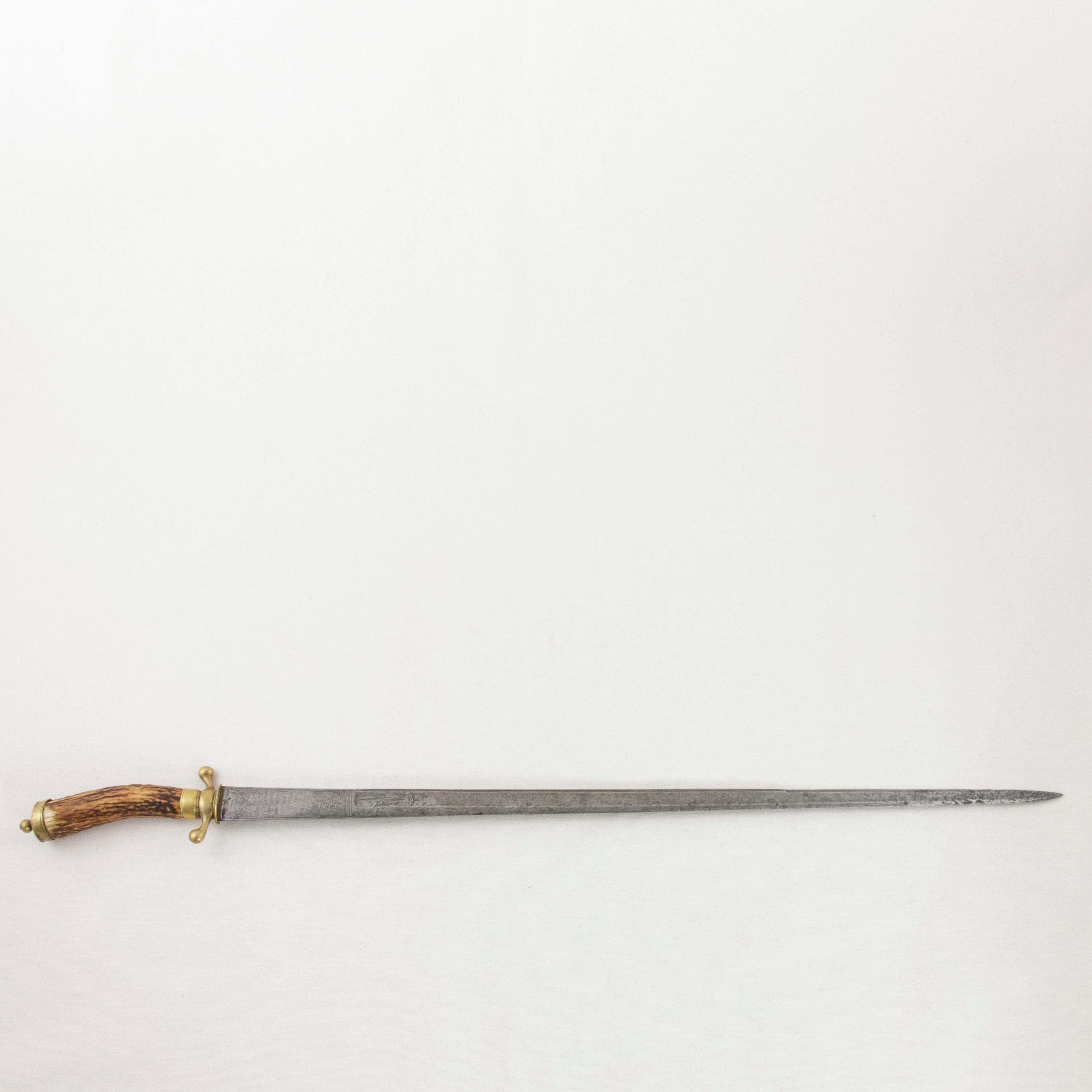 This mid-18th century French Louis XV period hunting short sword features a 26 inch long tapered steel blade engraved with a crown and star on each side indicating that this piece once belonged to a noble. An engraved hunting scene with a wild boar