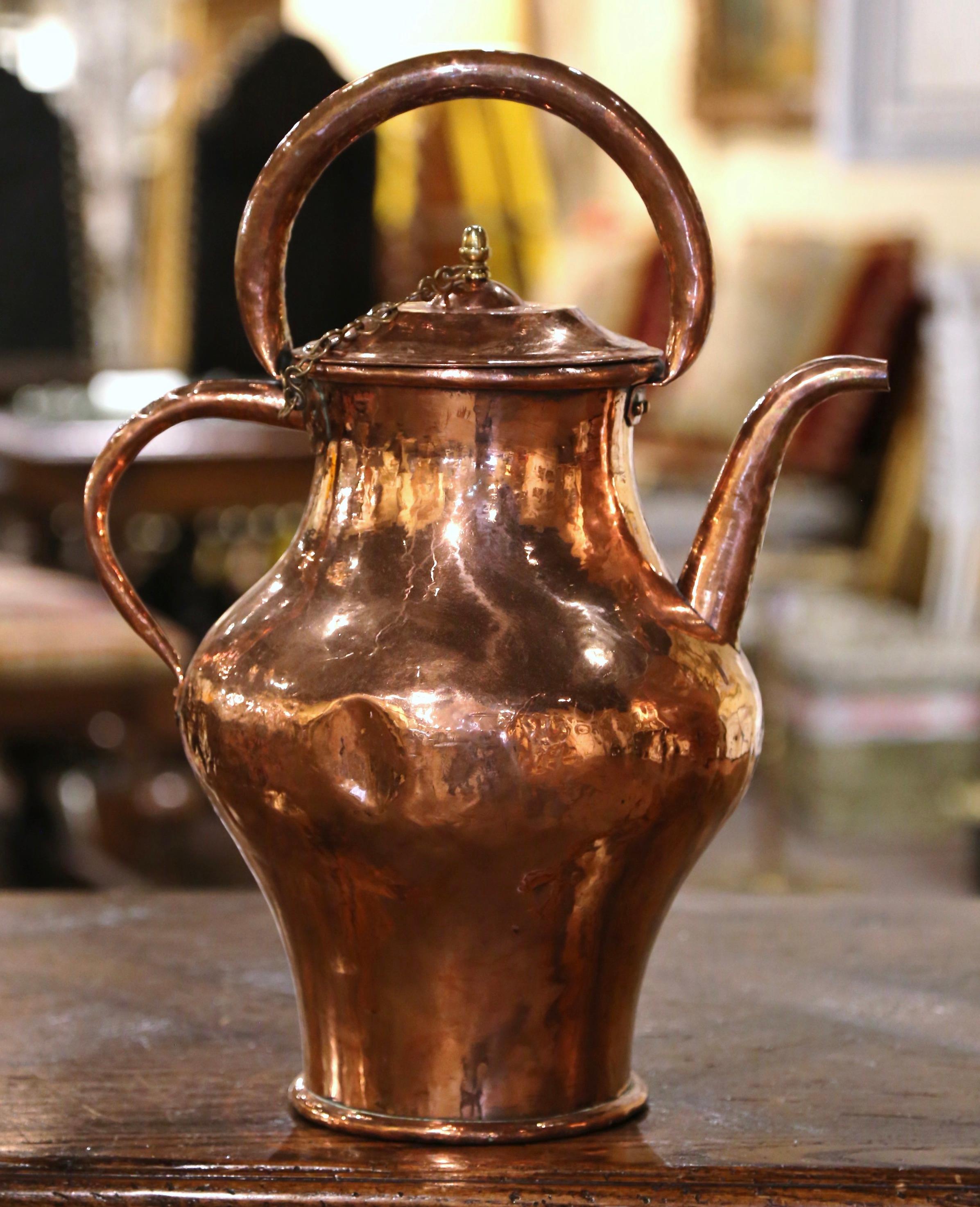 Bring an authentic French countryside touch to your kitchen with this tall antique copper hot water kettle. Crafted in Normandy, France, circa 1770, the decorative pitcher is round in shape and dressed with double handles attached with rivets; it is