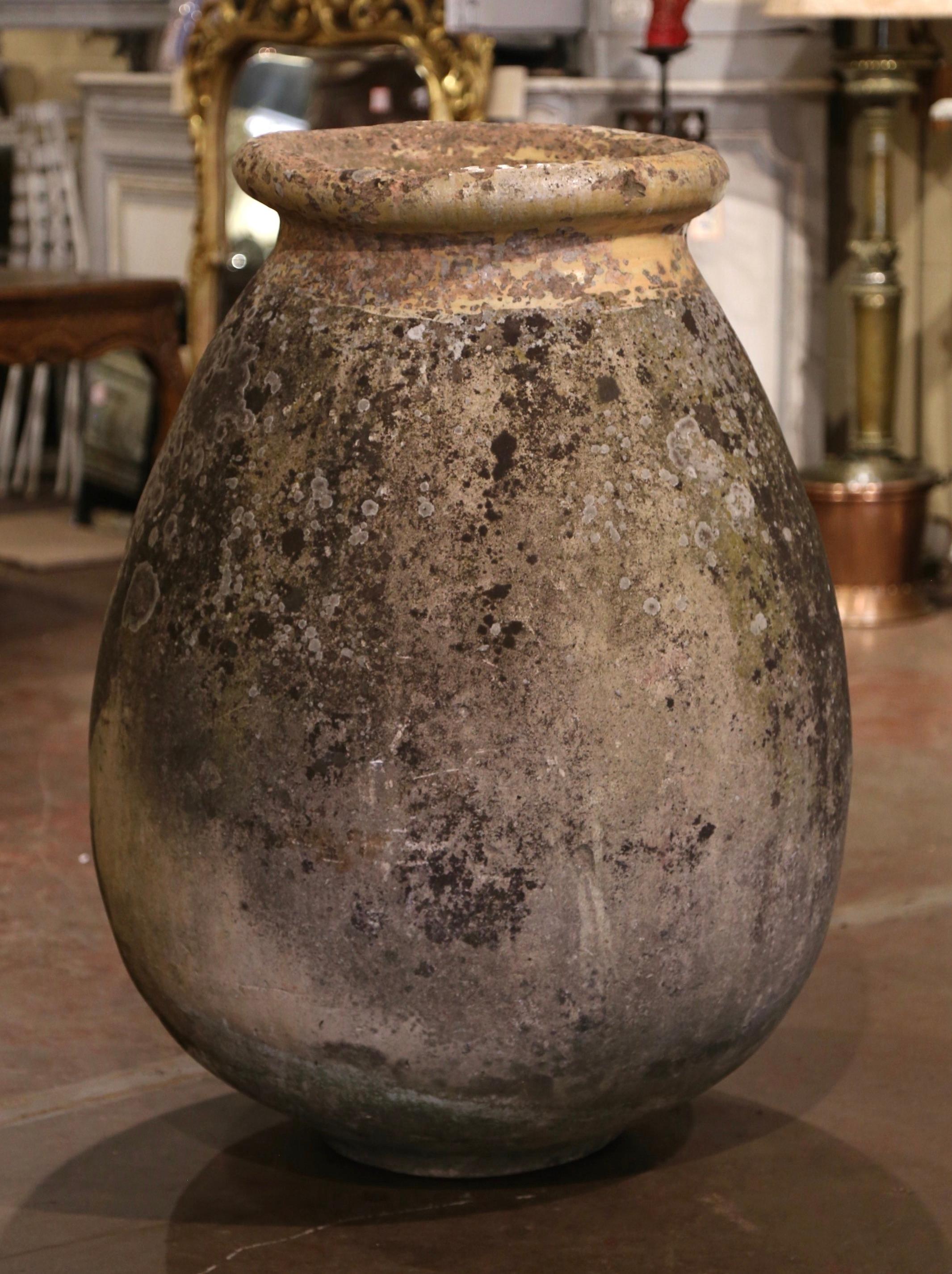 This large, antique earthenware olive jar was created in Biot, Southern France, circa 1760. Made of blond clay and neutral in color, the terracotta vase has a traditional round bulbous shape. The rustic, time-worn pot features a pale ochre glaze