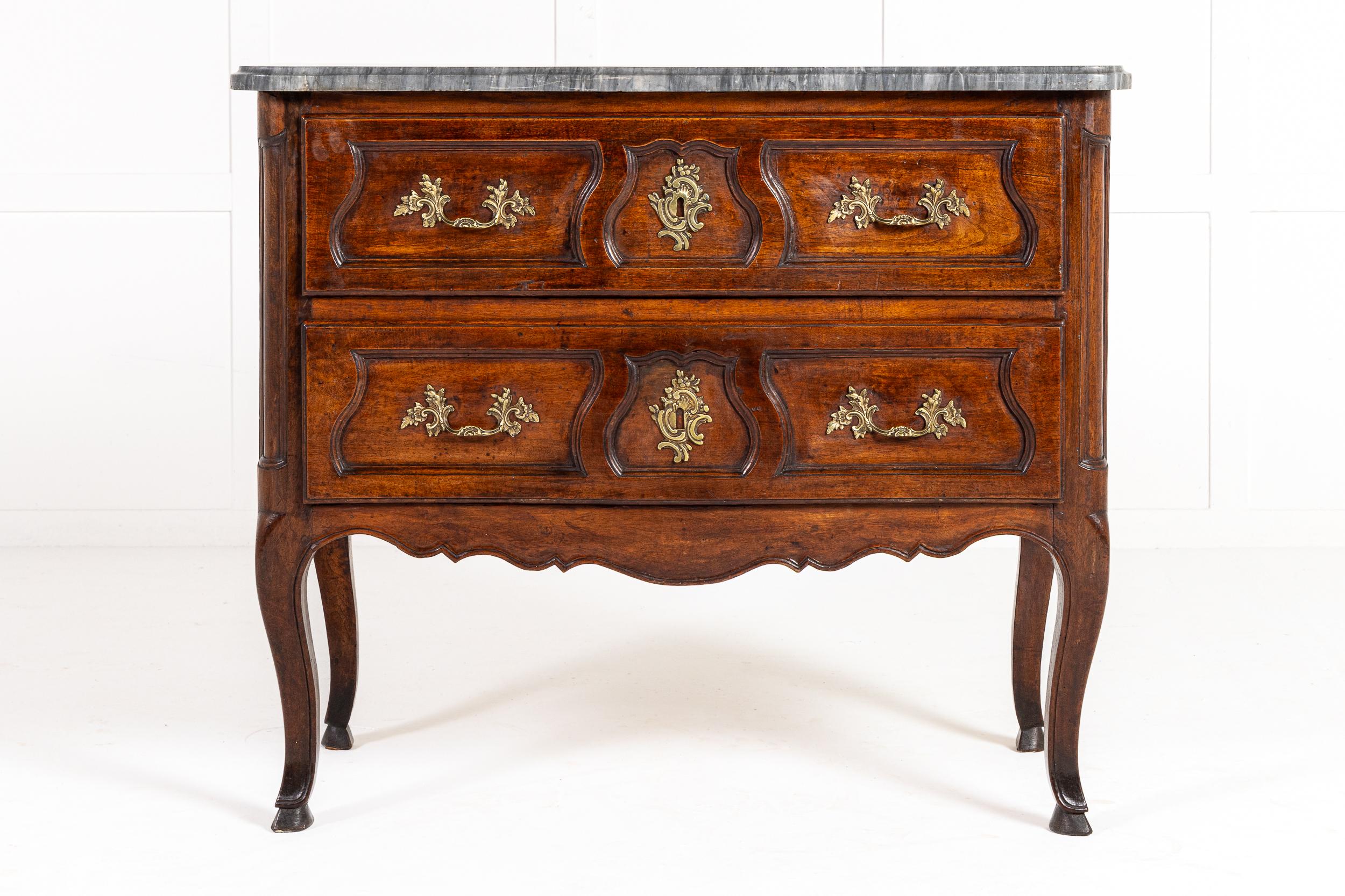 A Mid 18th Century French Provincial Walnut Commode with Original Grey Marble Top of Small Proportions.

This two drawer, walnut commode was conceived in the late rococo manner by a provincial maker in France. The original overhanging grey marble