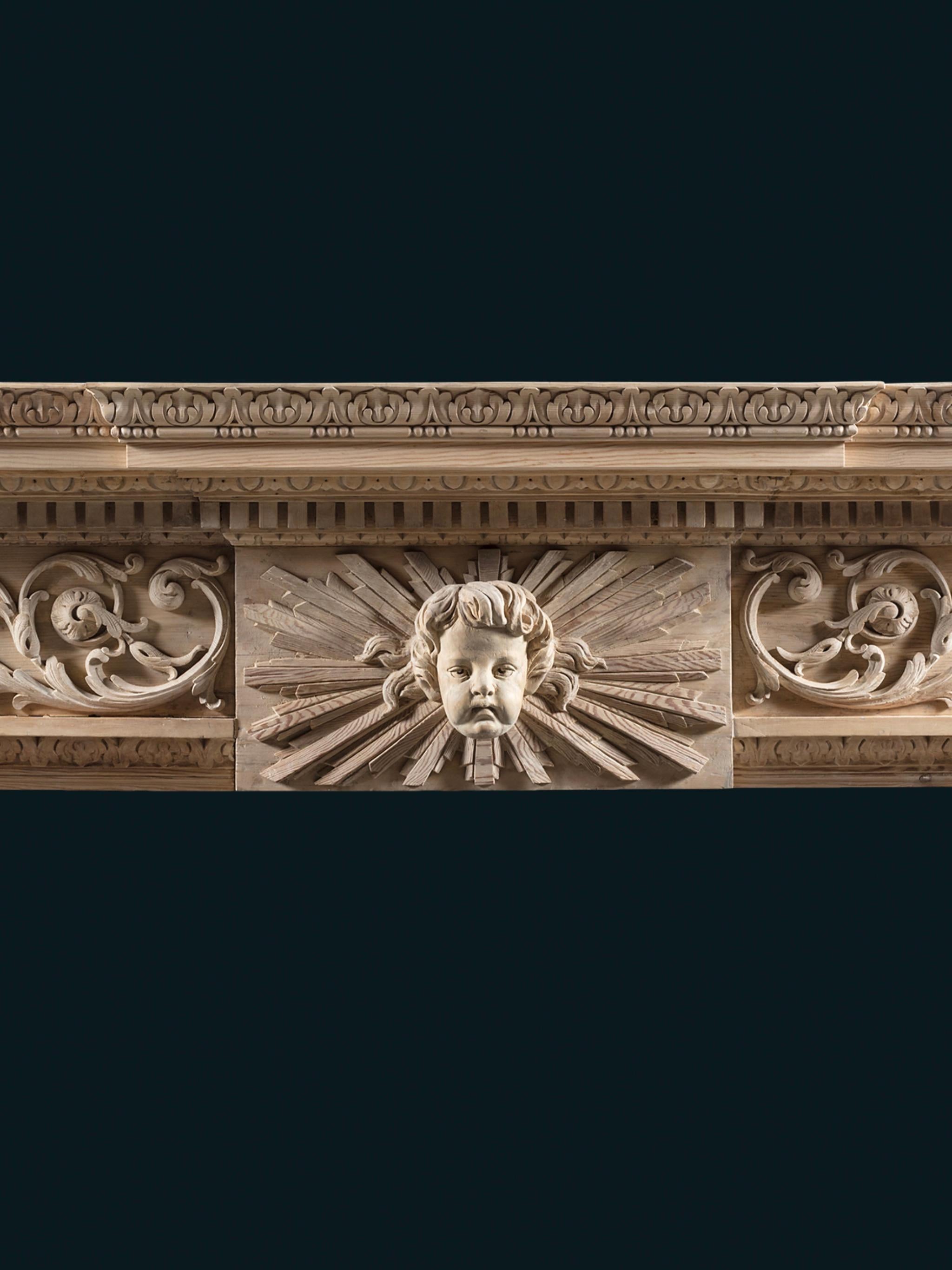 Belle cheminée en pin sculpté du milieu du XVIIIe siècle de George II. La tablette centrale est sculptée de la tête d'Aurora, Dieu de l'aube dans le soleil éclatant du nouveau jour, flanquée d'une frise enrichie de généreuses gerbes de feuilles
