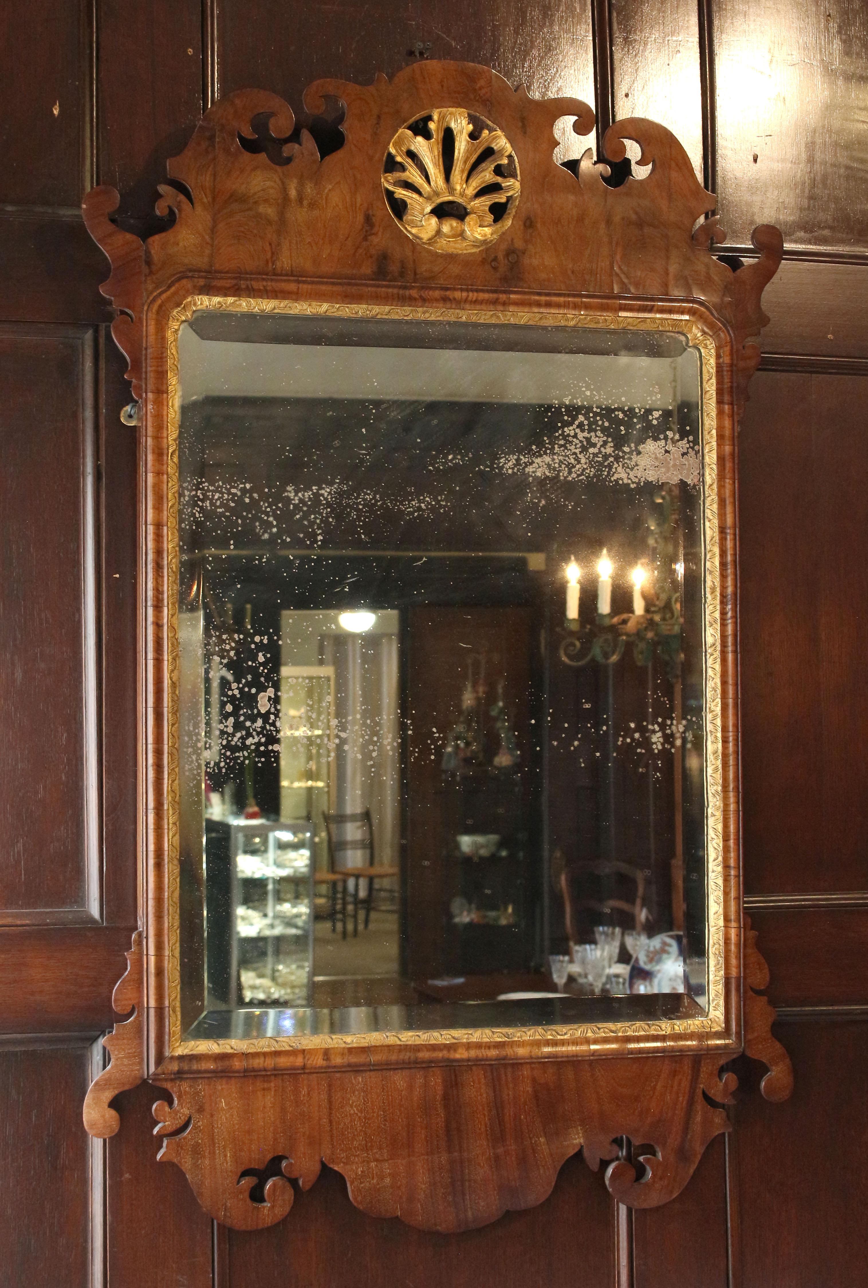 Miroir d'époque George II-George III du milieu du XVIIIe siècle, anglais. Noyer avec dorure parcellaire. Cartouche central rond et doré dans la crête supérieure bien formée. Plaque de miroir en verre biseauté à bordures dorées avec des dépôts de