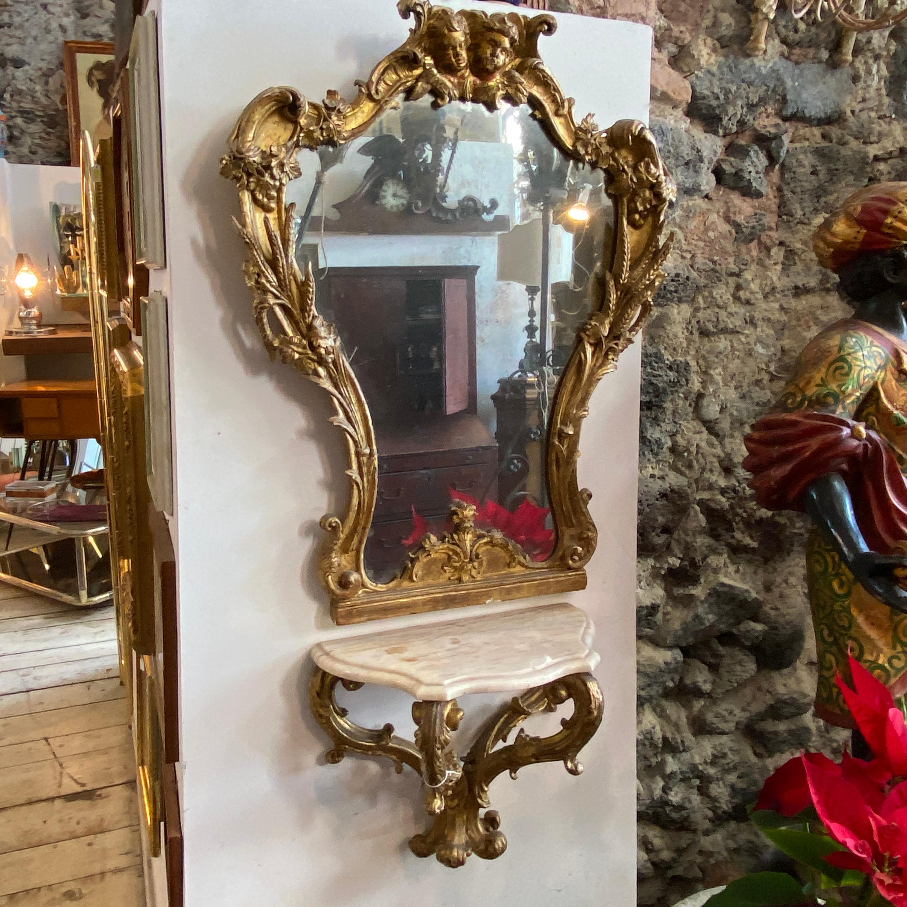 A superb baroque Sicilian wall console with his mirror. Giltwood of the two pieces have signs of use and age. It's all decorated with hand-carved angels and ears of corn, marble it's in perfect conditions. It's an amazing example of italian baroque