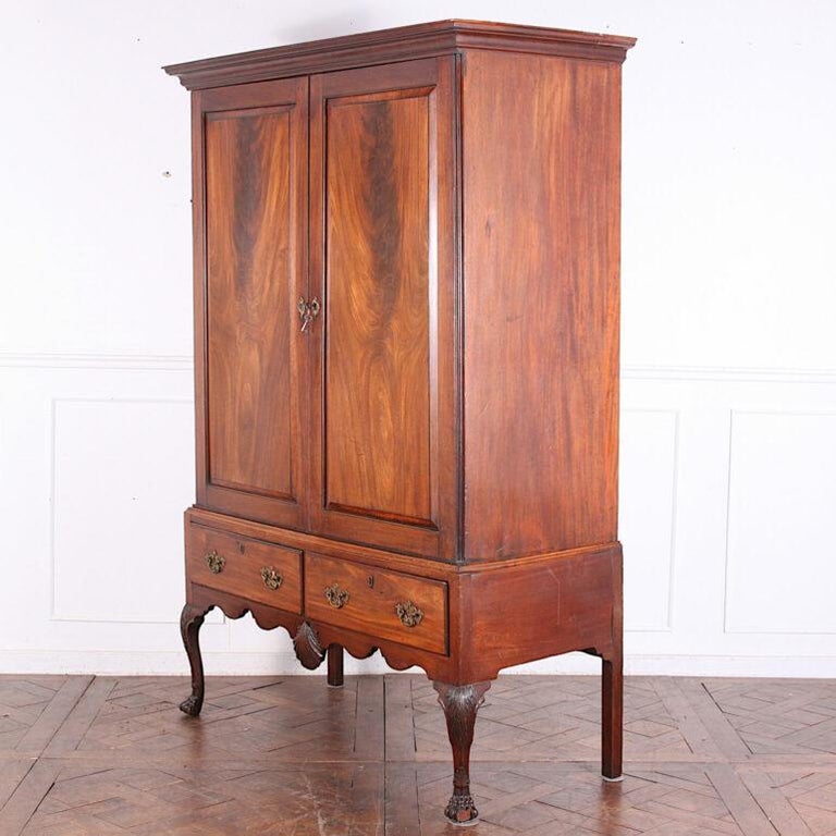 Irish solid mahogany George II cabinet on stand or linen press, the upper doors with flame mahogany fielded panels opening to several pull-out shelves and with a pair of oak-lined drawers below.
Upper cabinet with pull-out surfaces; inner door