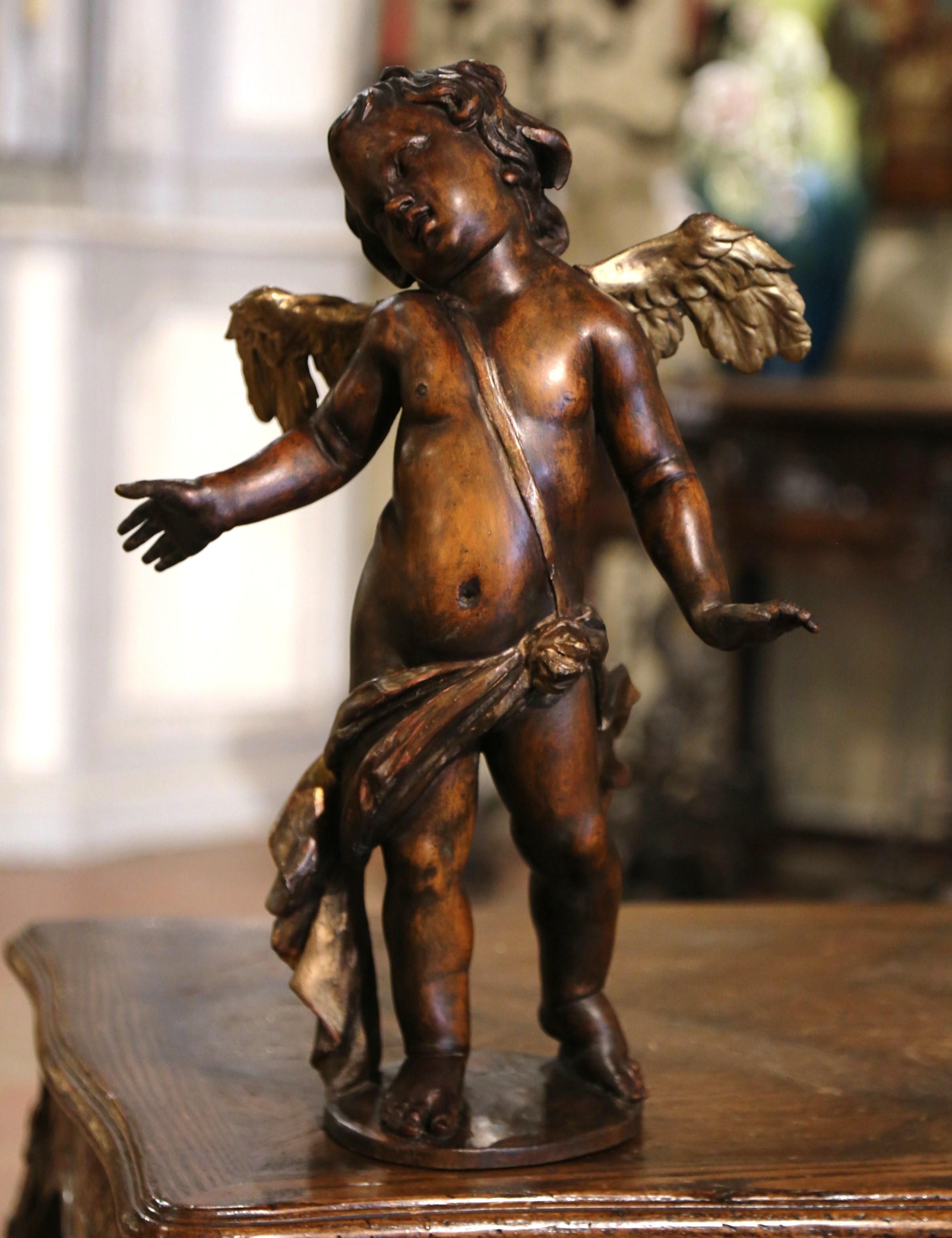 This elegant antique putti figure was carved in Italy, circa 1770. Standing on an oval base, the detailed statue features a young boy with wings his head turned to the side. The adorable cherub is wearing traditional clothing wrapped around his