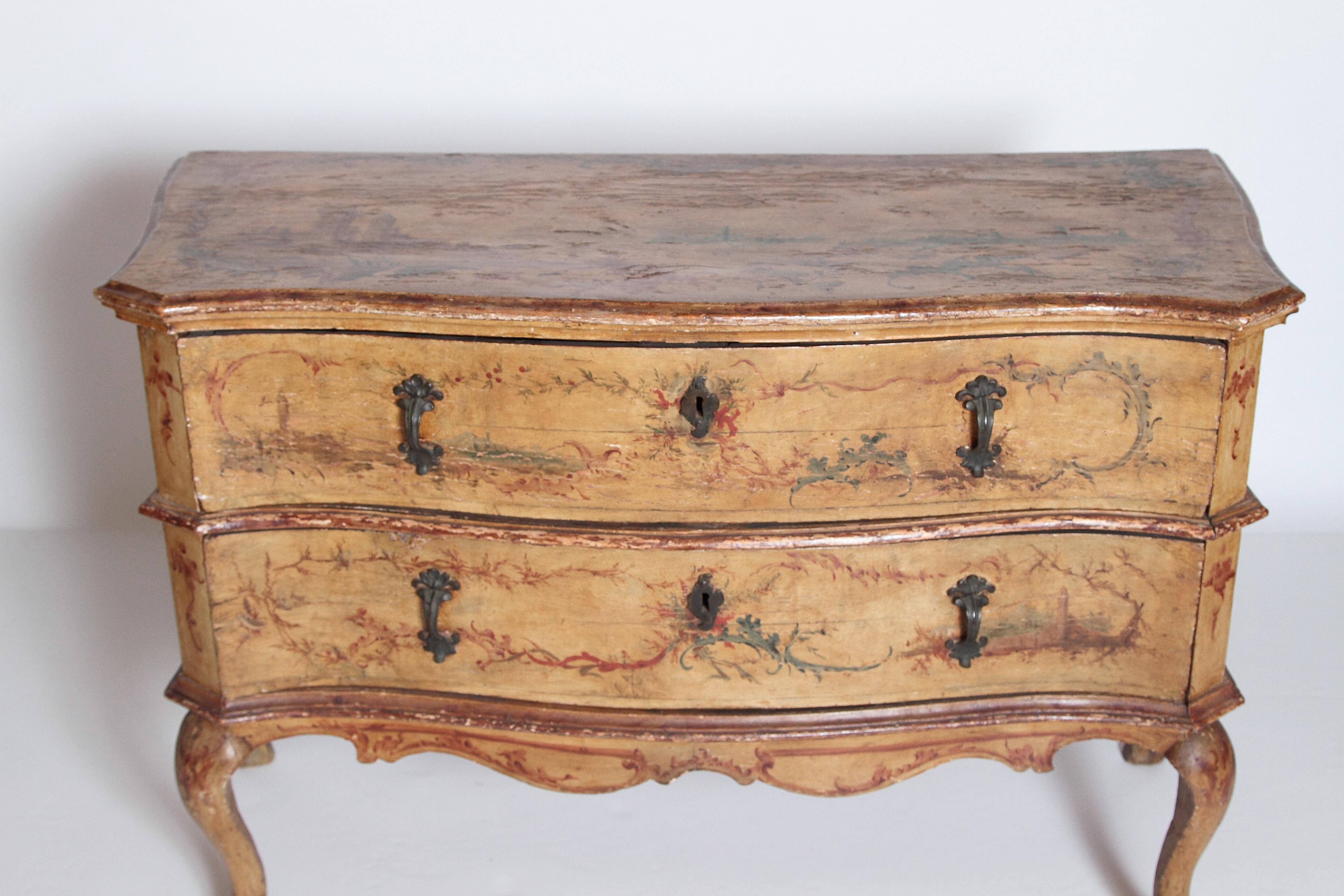 Mid-18th century Italian painted two-drawer commode with floral decoration. A serpentine molded top with canted sides and shaped front over double stacked drawers. Each drawer has two metal floral pulls and a key hole. A scalloped stretcher is