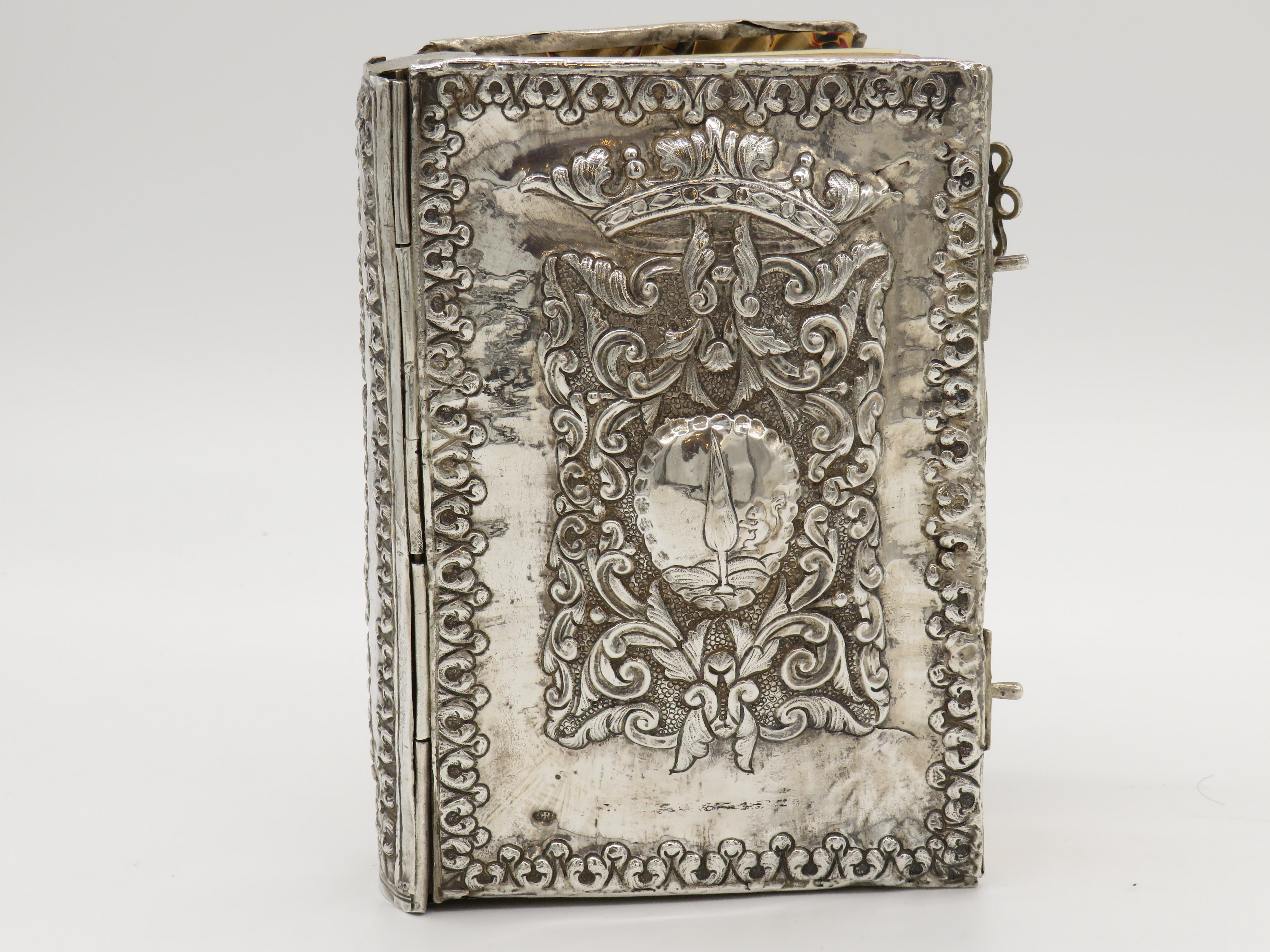 An 18th century Italian silver book binding. An impressively designed, this book binding is formed by two, nearly identical covers, each embossed with a panel of scrolling foliage topped by a coronet and enclosing armorials. Chased leaf-tip forms
