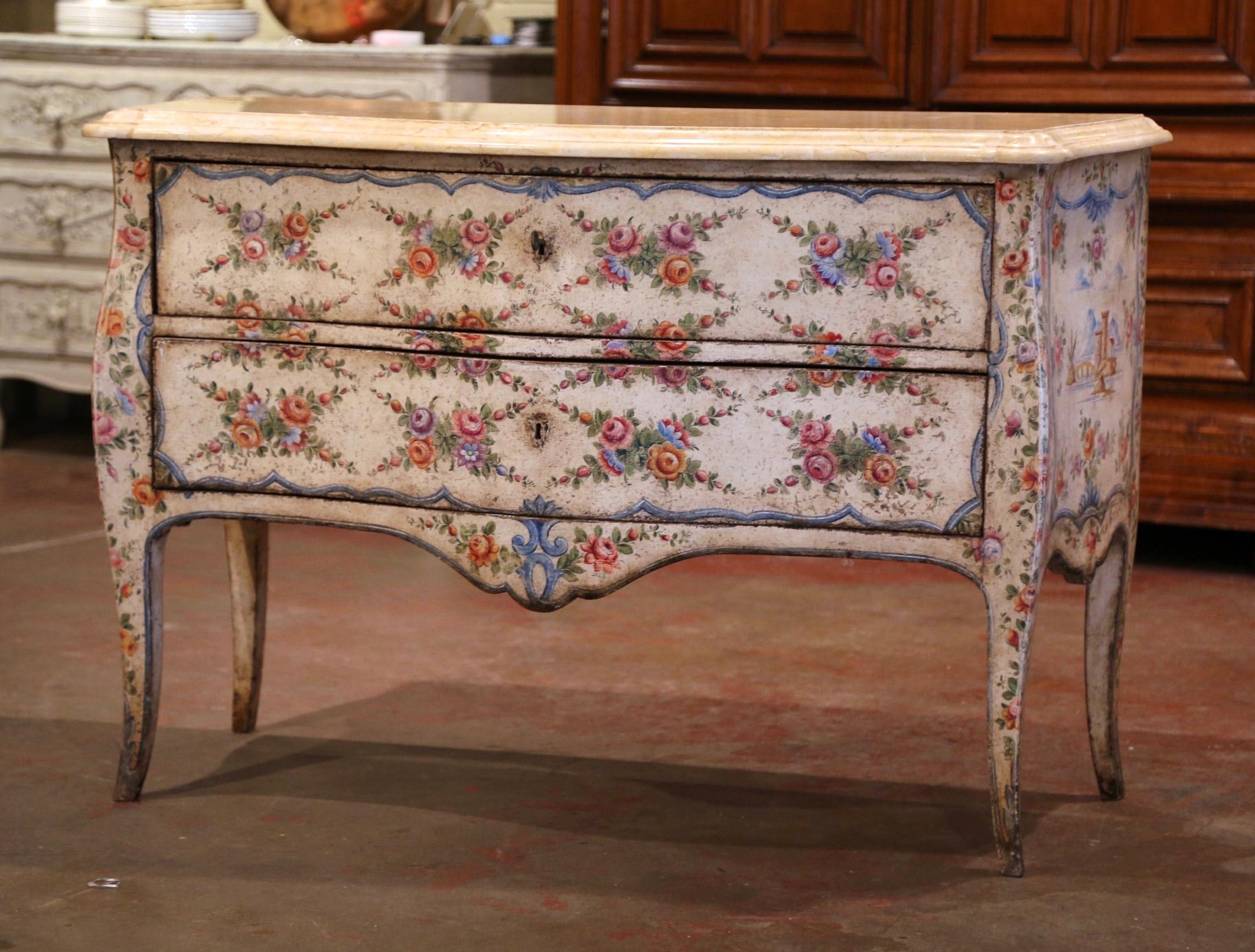 This elegant antique commode was crafted in Venice, Italy circa 1760, standing on four curved legs over a scalloped apron, the chest has two bombe drawers across the front decorated with hand painted floral motifs. The top is dressed with a