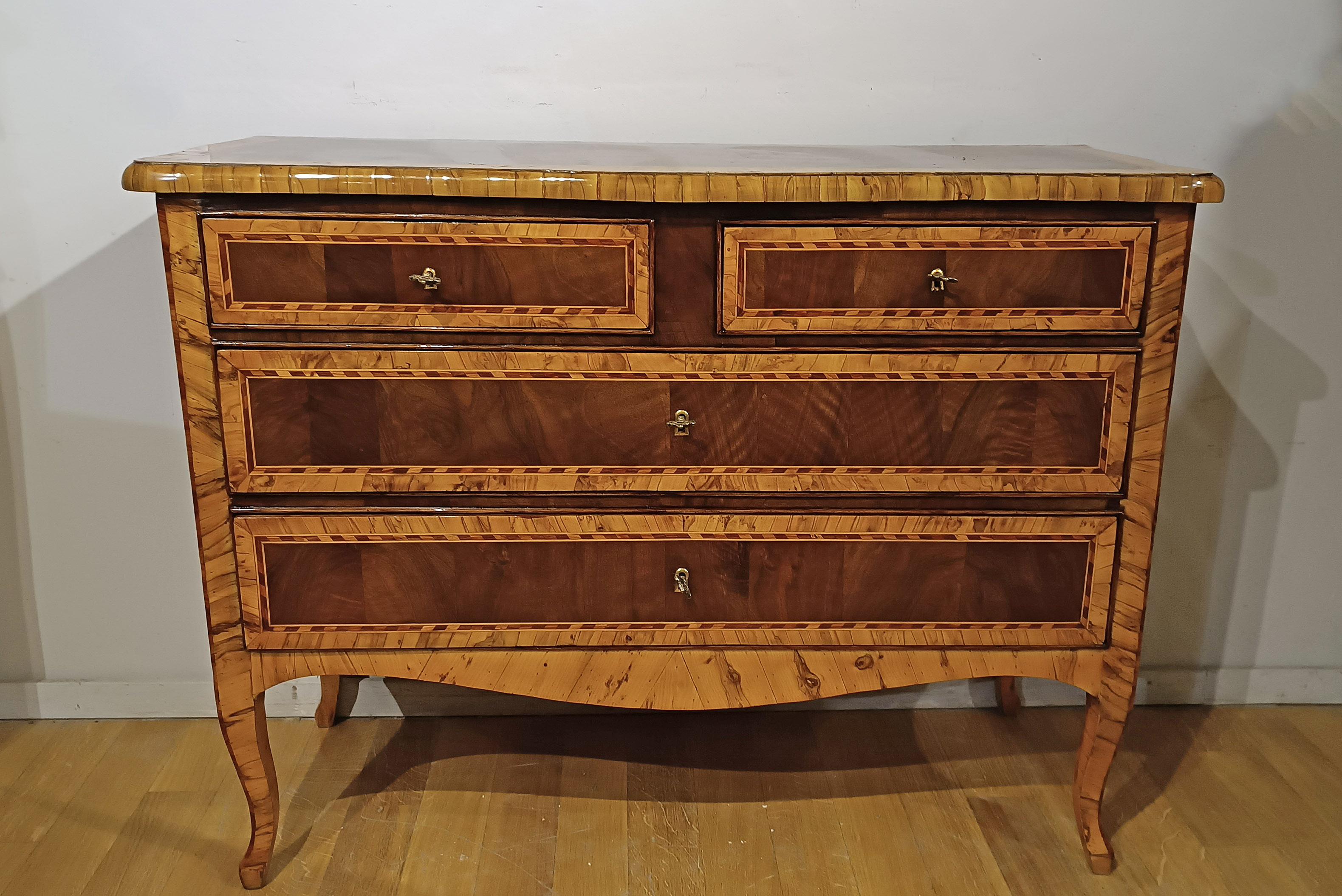 This Louis XV chest of drawers, completely veneered in walnut and olive wood, is a remarkably elegant and refined piece of furniture. Its distinctive feature is the thick strip present, which denotes great quality and attention to detail in the