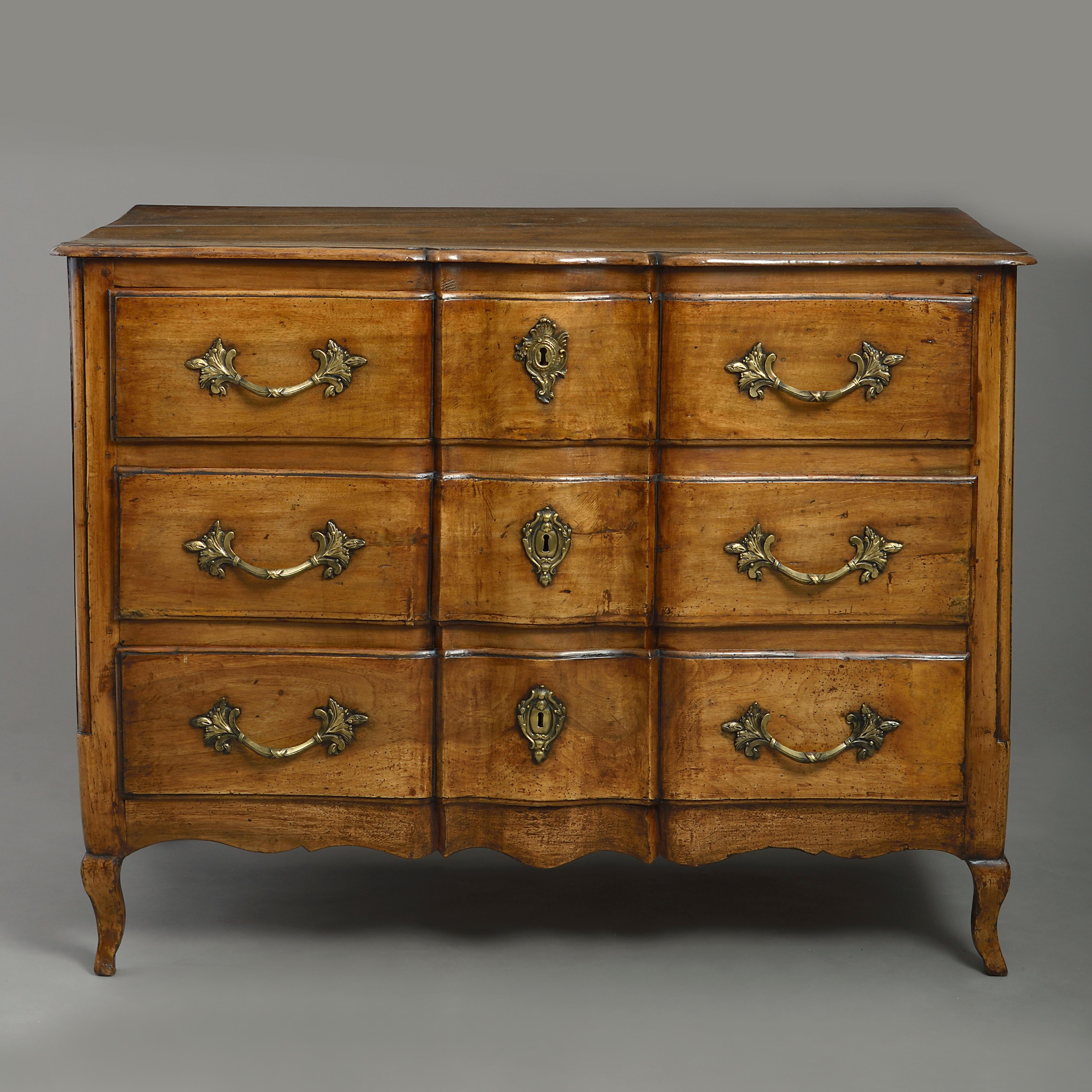 A fine mid-18th century Louis XV period walnut commode, the shaped overhanging top above three ripple moulded drawers, having foliate brass handles and cartouche form lock escutcheons, all raised upon cabriole legs.