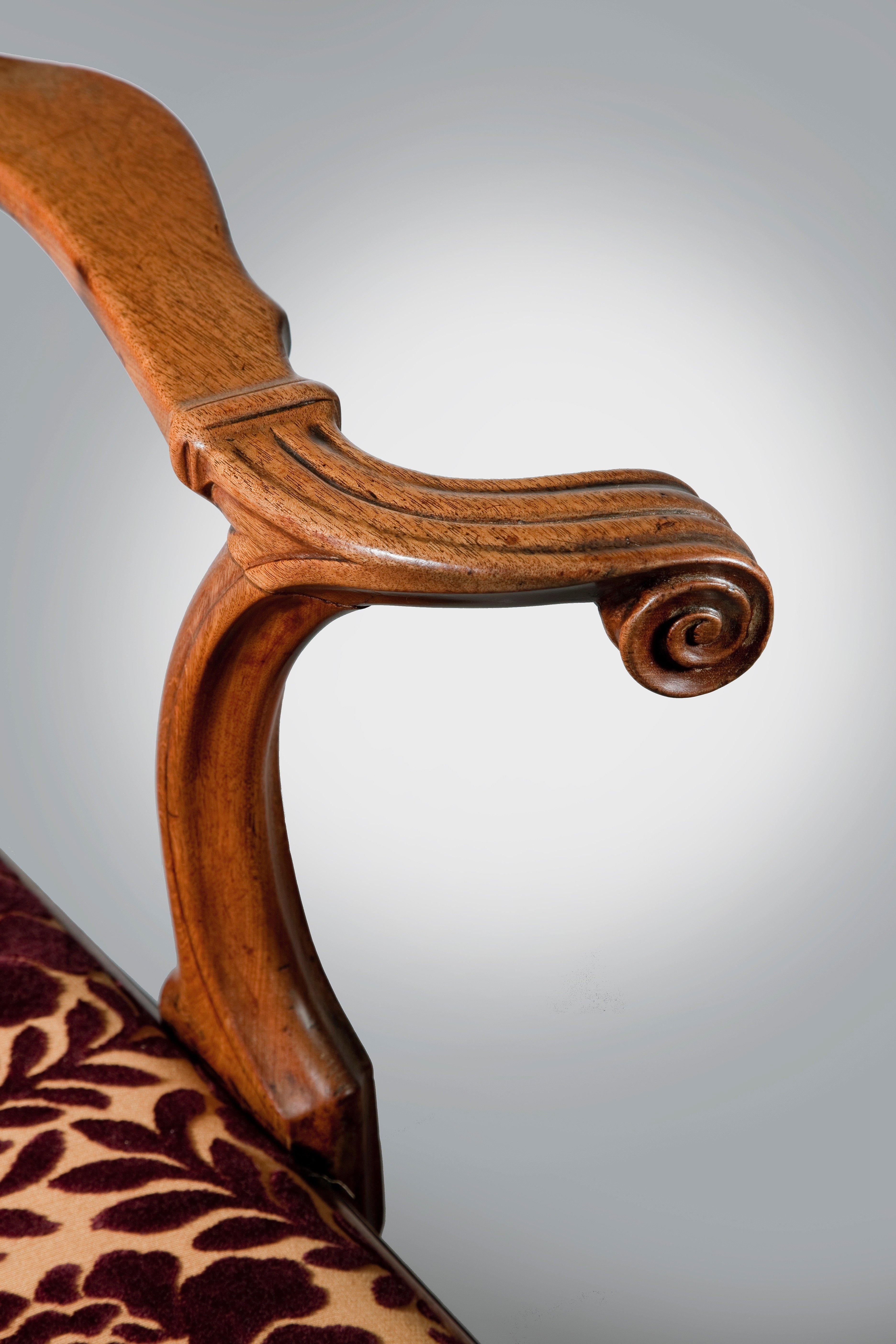 A George II period mahogany open armchair in the manner of Giles Grendey, with unusual outswept scroll and cuff arms, nicely scribed detail to the back and gently swept crest rail terminating in scroll ears. It is a wonderfully drawn, well