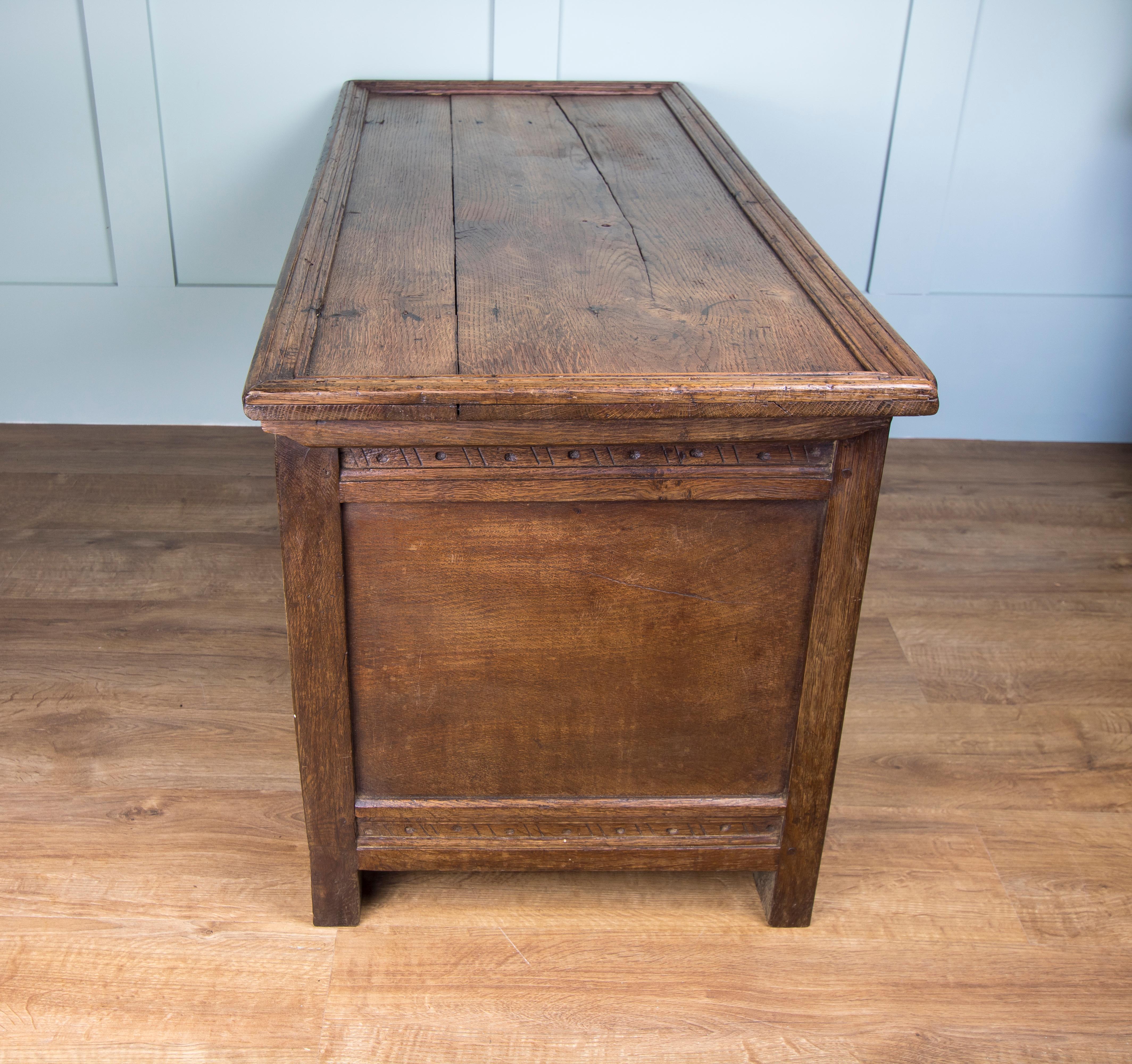 This sturdy oak joined coffer believed to date from the mid-18th century. Decorative carved front featuring three panels. Hinged three plank top with original ironmongery but no key. We are investigating having a key made for it, so please message