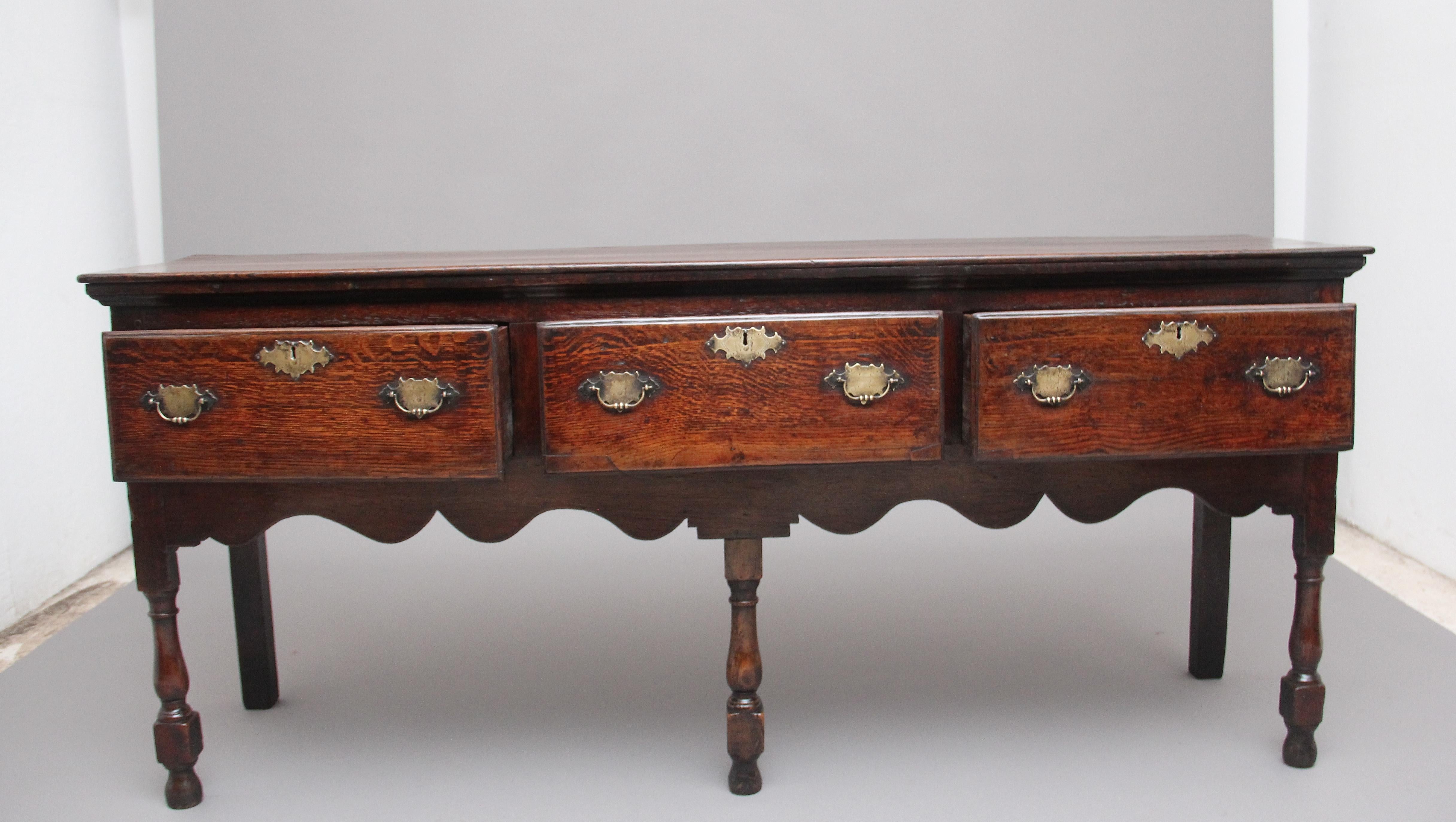 18th century oak dresser with a lovely patina, the moulded edge top above three deep drawers with brass plate handles and escutcheons, nice decorative shaped frieze to the front and sides, supported on front turned legs and rear square legs, circa